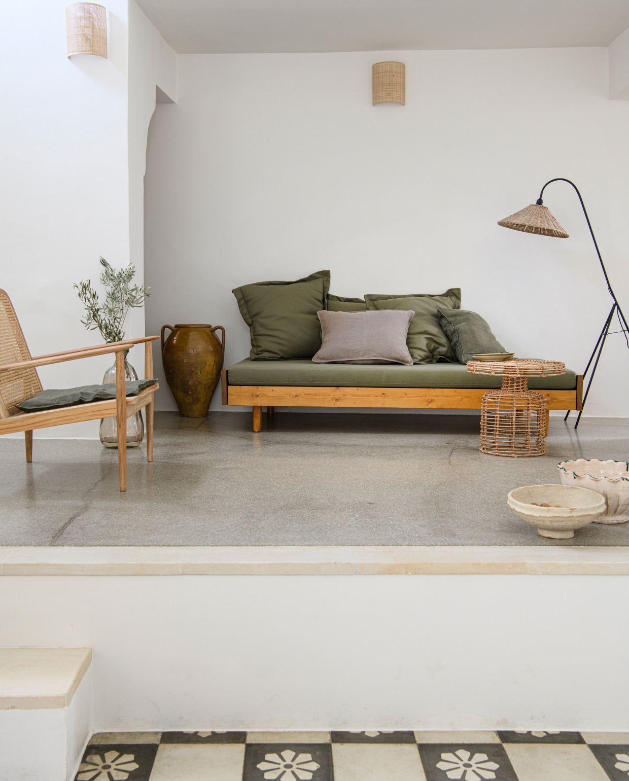 Divan gemaakt door lokale timmerman. Fauteuil Zara Home. Wandlampen Sklum. Rotan bijzettafel en lamp lokale markt. Overig tweedehands. vtwonen special binnenkijken 06-2023 | productie Insidehomepage | fotografie Louis Lemaire | styling Marit Saladini
