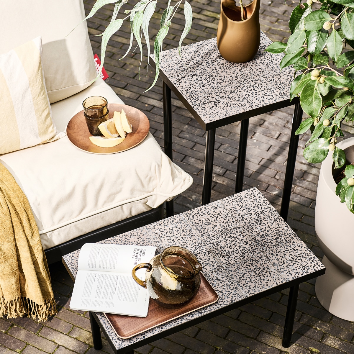 Modulaire loungeset Paletti van Fatboy, kunststof frame met waterafstotende kussens € 899,-, bruine stenen vaas Nicita van Bloomingville € 58,90 (vtwonen.be/shop). Plaid € 12,99, blauw gestreept kussen € 17,99, geel gestreept kussen € 17,99, glazen karaf € 29,99, houten onderzetter € 5,99, houten dienblad € 17,99, drinkglazen € 5,99 (zarahome.com). Overig privébezit. vtwonen 08-2023 | styling en uitvoering Sanne Ketelaar | fotografie Sjoerd Eickmans