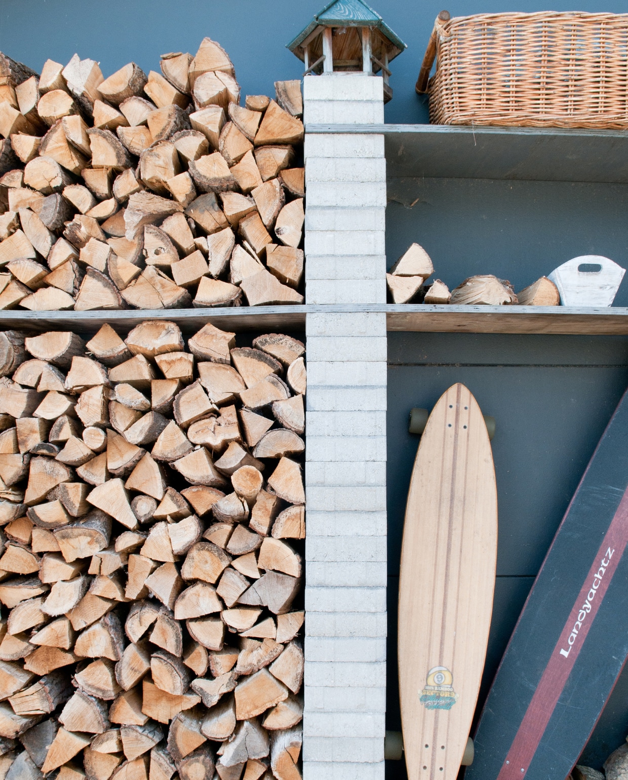 Buiten in de tuin: de houtopslag. Ernaast: twee longboards van Natasha. vtwonen 03-2017 | styling Irene van den Brink | fotografie Suzanne Paap