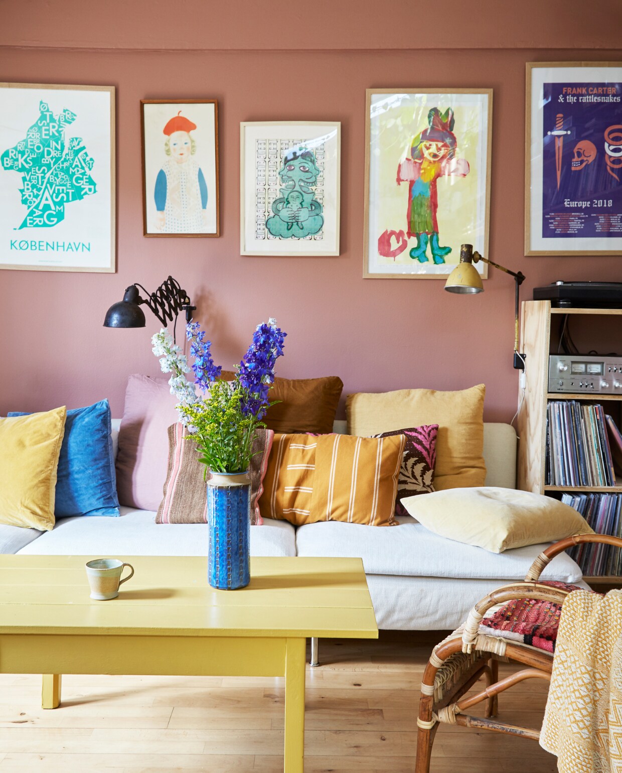 Muurverf Warm Blush van Jotun. Kopenhagen-poster Kortkartellet. Meisje met groene laarzen oude kinderschildering van Mathilde. Letterpuzzel Maduro. Bank Ikea. Salontafel zelfgemaakt. Blauwe vaas uit pottenbakkerswinkel in Herlev. Rieten stoel My Home Møbler. Marokkaanse kussens Sweet Treat. Andere kussens zelfgemaakt en Ikea. Overig onbekend. vtwonen special binnenkijken 06-2023 | productie Living Inside | fotografie Anitta Behrendt | styling Rikke Graff Juel