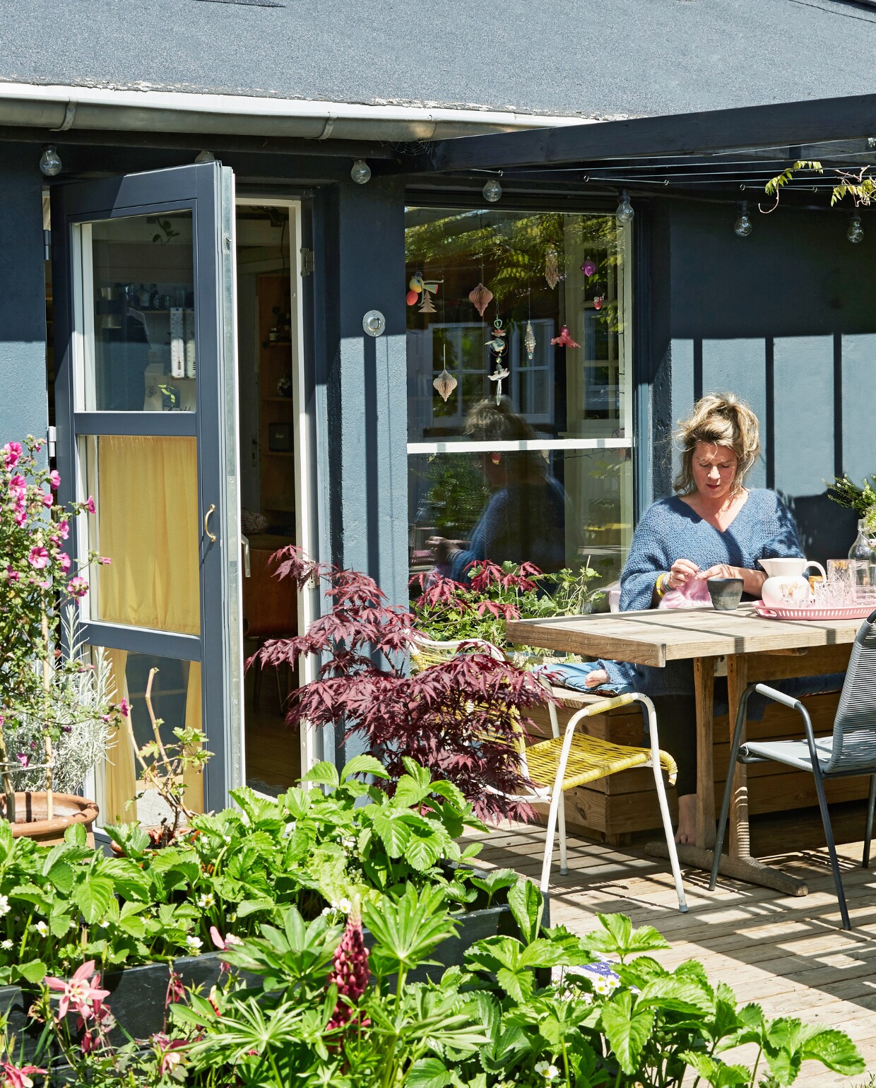Buitentafel gemaakt van planken uit het keukenplafond. Drinkglazen Smukt Brugt. Jampotten gebruikt als drinkbekers. Bloemenkan en tuinstoelen tweedehands. vtwonen special binnenkijken 06-2023 | productie Living Inside | fotografie Anitta Behrendt | styling Rikke Graff Juel