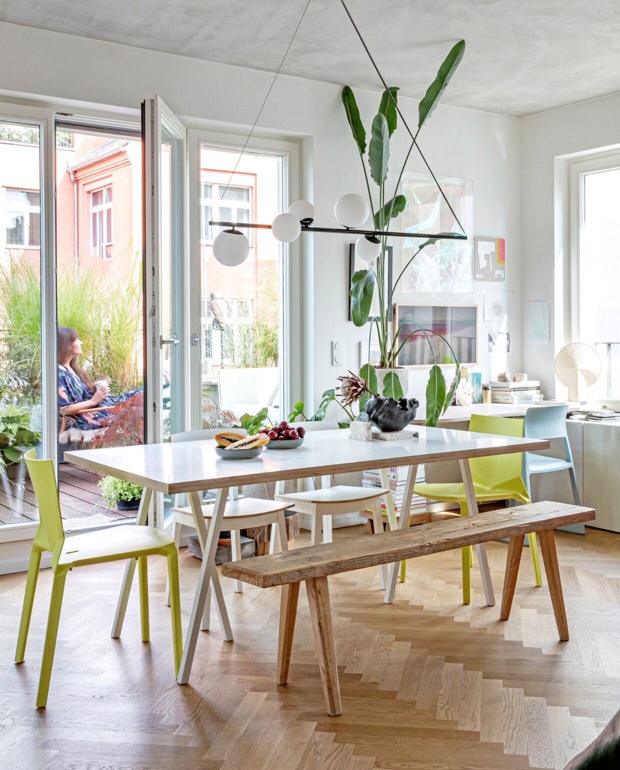 Tafelpoten Loop Stand en tafellamp in vensterbank Pion van Hay. Tafelblad Schreiner. Gele stoelen Kristalia Plana. Witte stoelen en wandkast Besta van Ikea. Houten bank Studio Elliot White. Hanglamp Vetro van Made. Televisie The Frame van Samsung. Lichtblauwe stoel Tip Ton van Vitra. Overig onbekend. vtwonen special binnenkijken 06-2023 | productie &amp; fotografie Anne-Catherine Scoffoni | styling Raini Peters