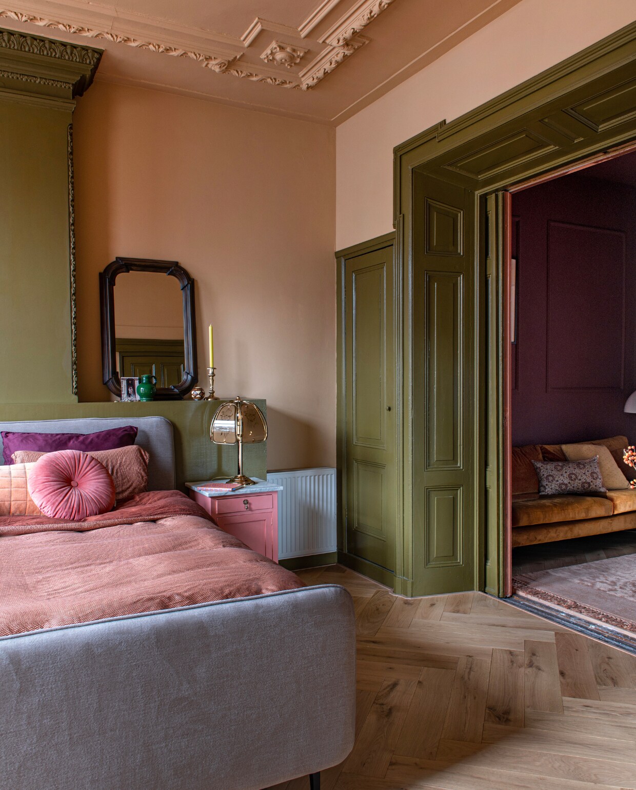 Verf houtwerk en schouw Hunter, muurverf Teddy en verf vintage nachtkast Electric Pink van Lab Paint. Bed Swiss Sense, dekbedovertrek Beddinghouse, rond kussen en geel kussen Essenza. Bank Sofacompany, gebloemd kussen Karwei, vloerkleed BePureHome. Spiegel, tafellamp en kandelaar vintage. Visgraatparket Blank Geolied Eiken van vtwonen via Karwei. Overig onbekend. vtwonen 09-2023 | productie De Binnenkijkers | styling Jeske Weel | fotografie Caroline Coehorst