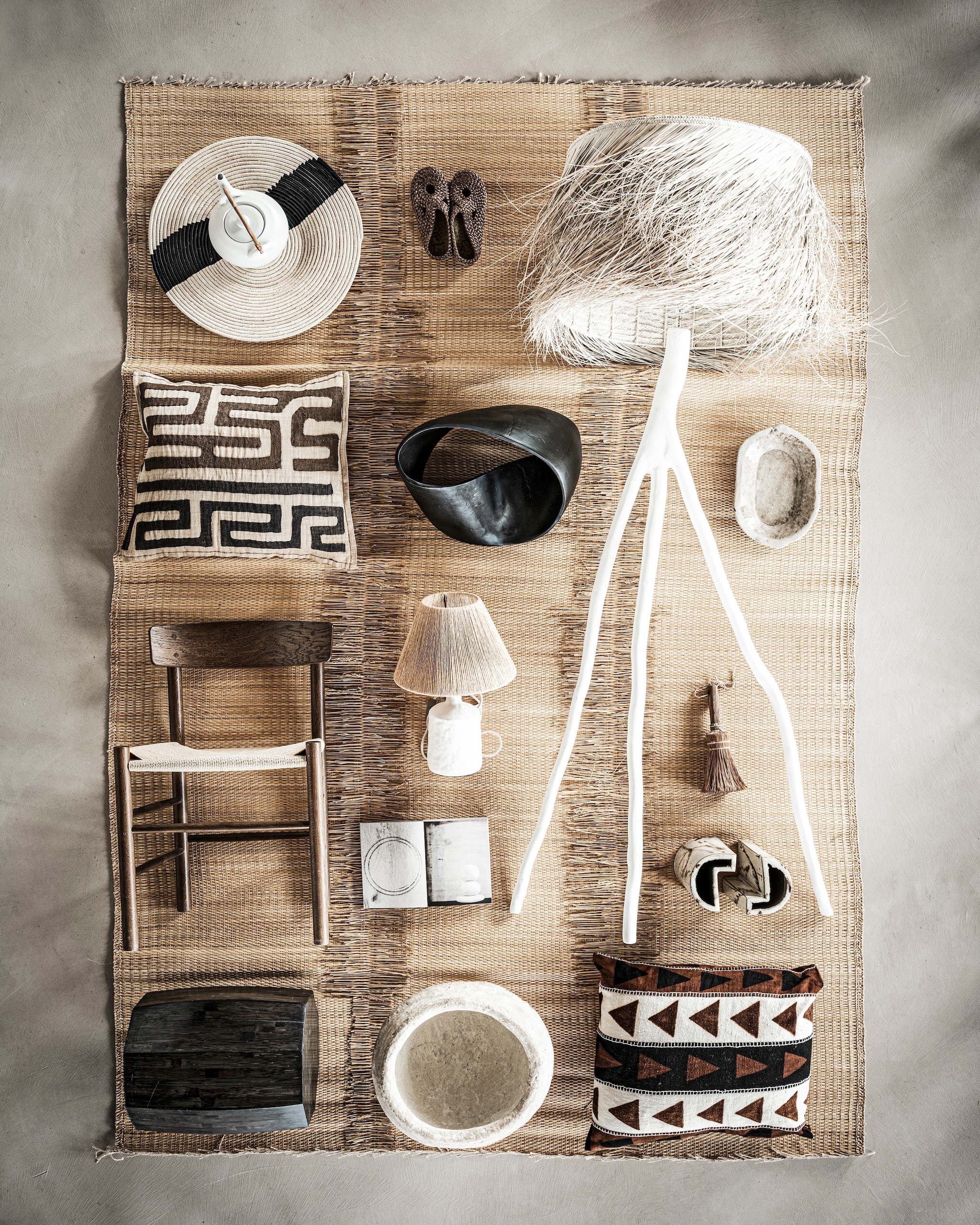 Gevlochten mat uit Tunesië € 450,-, raffia mand linksboven uit Ugunda, 56 cm € 119,-, staande lamp van palm, 200x40 cm € 650,- (couleurlocale.eu). Witte theepot € 79,-, slippers Illetes Bronze € 105,-, boek € 65,-, kussen rechtsonder € 199,- (sukha.nl). Kussen linksboven Unique Pieces € 220,- (mlfabrics.nl). Zwart sierobject € 491,73 (badenbaden.nl). Marmeren schaal rechts van de stalamp € 79,90 (letoile.store). Tafellamp € 79,99 (zarahome.com). Witte mand € 47,50, kwast bij lampenpoot € 39,50 (aurapeeperkorn.com). Overig bezit van de locatie (republiekbloemendaal.nl). fotografie Sjoerd Eickmans styling Liza Wassenaar