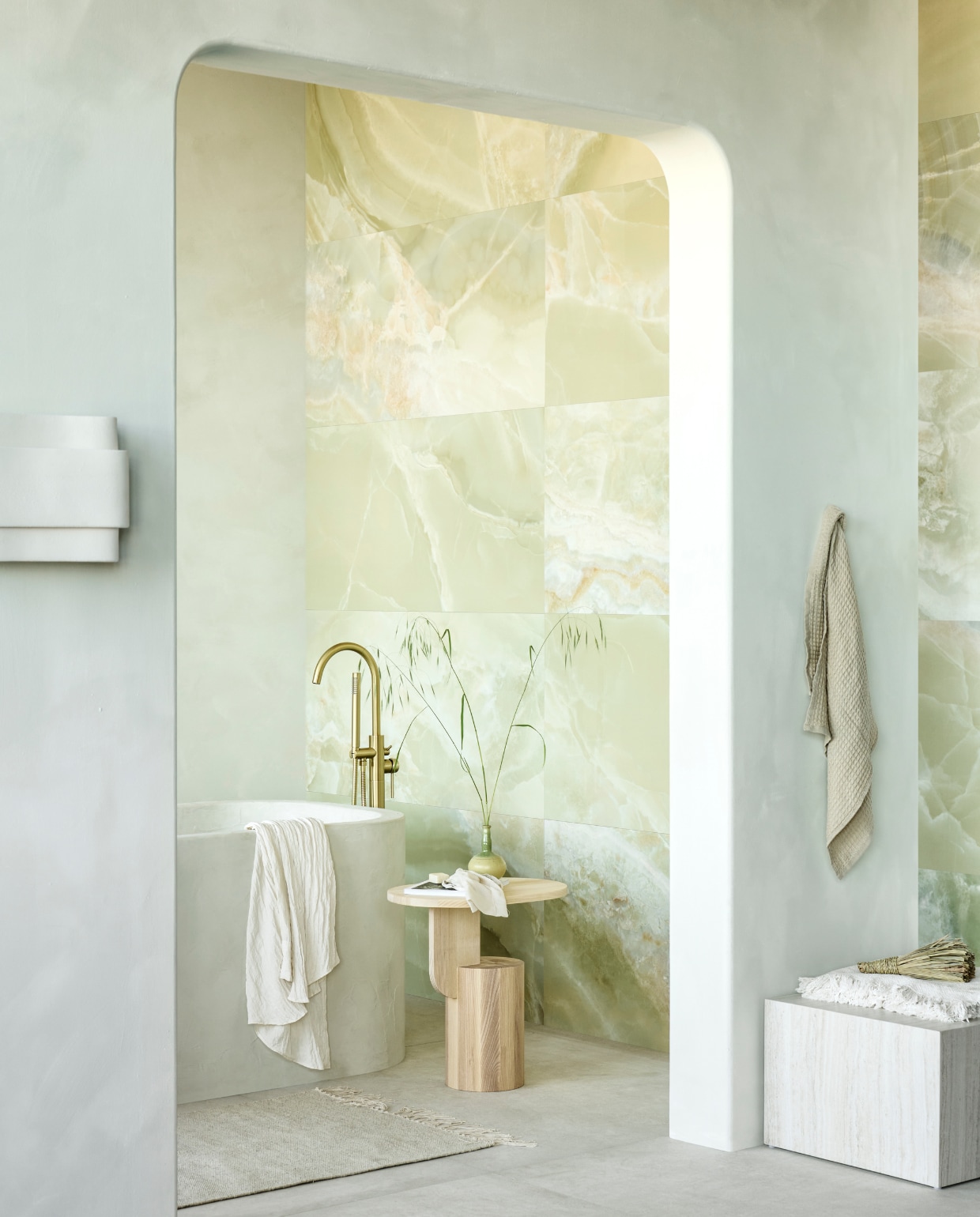 Op de wand tegels Onyx Jade Green, 60x120 cm, per m² € 92,50. Op de vloer tegels Raw White Mat, 120x120 cm, per m² € 92,50.M.m.v. pure-original.com (muurverf  Casablanca), tegeldepot.nl (vrijstaande badkraan van Boss &amp; Wessing in geborsteld goud), vtwonen.nl/shop (bijzettafel Insert van Ferm Living, wandlamp van Serax, vierkante salontafel van Fonq),  hm.com (wollen badmat, handdoek), ikea.nl (plaid). Overig privébezit. vtwonen 09-2023 | productie Tanja Saarberg | styling Sanne Ketelaar | fotografie Sjoerd Eickmans