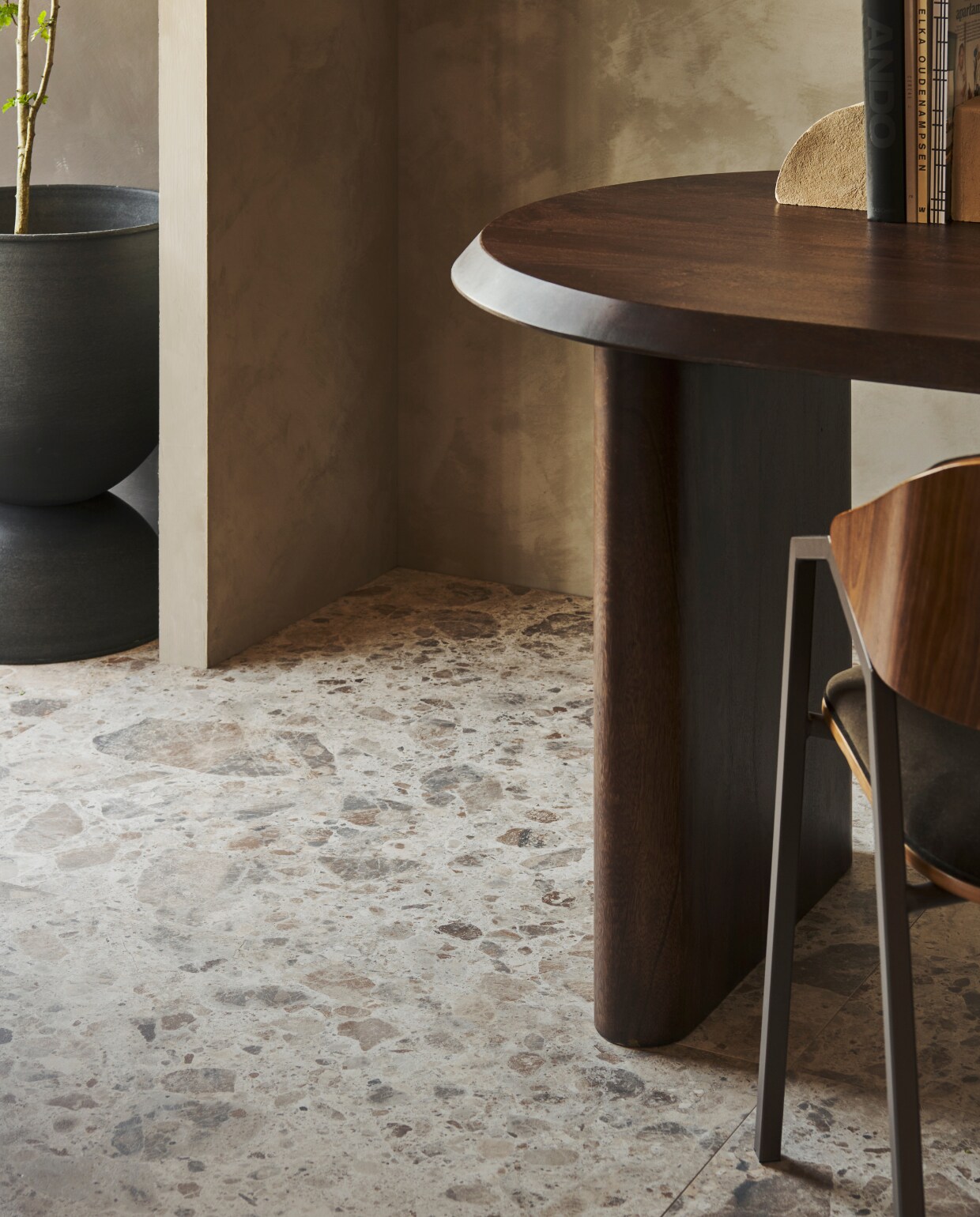 Tegels Composite Sand Mat, 120x120 cm, per m² € 82,50.M.m.v. pure-original.com (muurverf Artisan Tan), vtwonen.nl/shop (stenen ornamenten en bloempot van Ferm Living), basiclabel.nl (mangohouten tafel Ellips van vtwonen, stoel Clan van BePureHome). vtwonen 09-2023 | productie Tanja Saarberg | styling Sanne Ketelaar | fotografie Sjoerd Eickmans