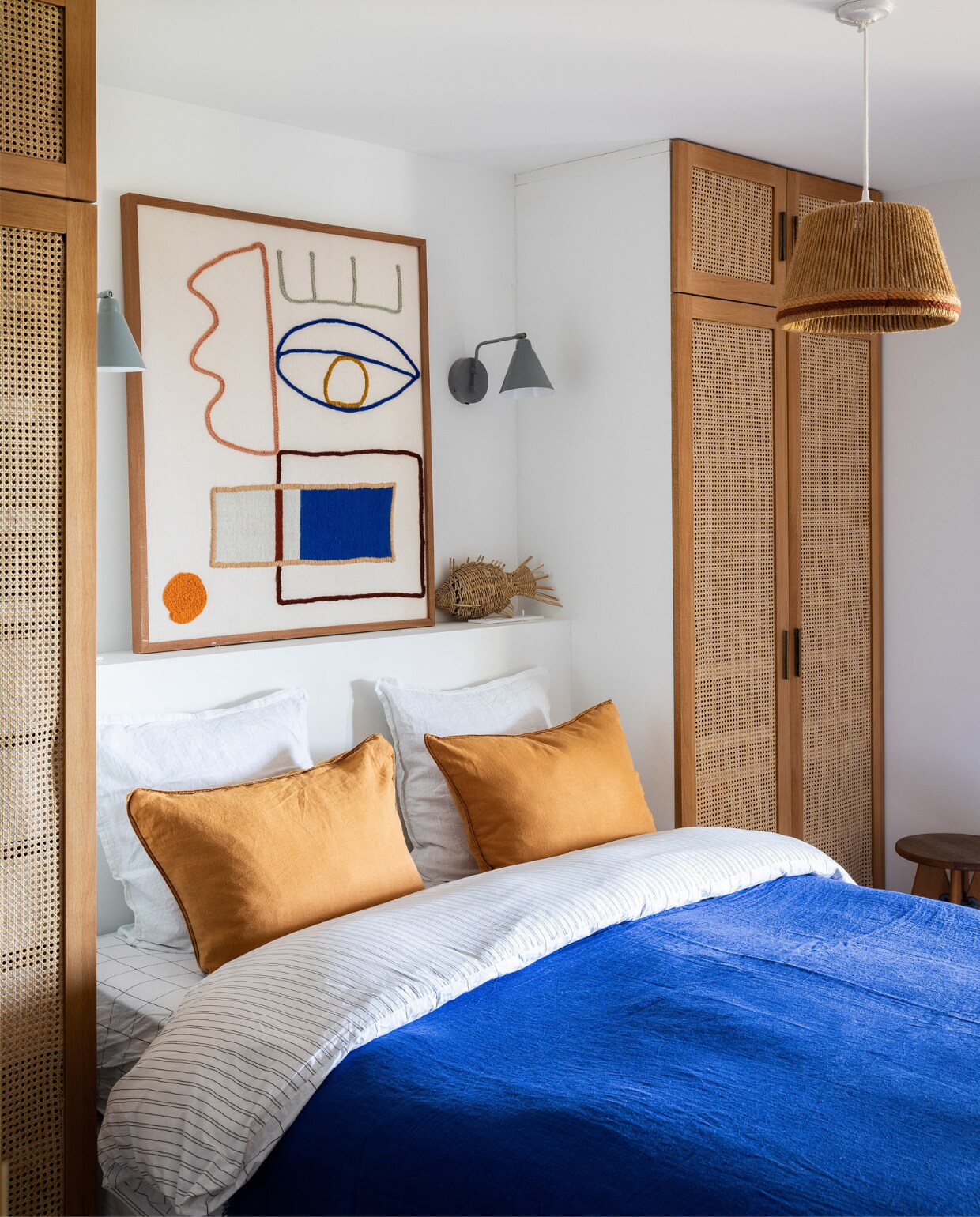 Kledingkasten op maat gemaakt. Kunstwerk LRNCE. Rieten vis cadeau.Wandlampen Serax. Gele kussens en beddengoed La Redoute. Sprei Maison de Vacances. Hanglamp vintage. vtwonen 07-2023 | productie &amp; styling Marie Maud Levron | fotografie Yann Deret