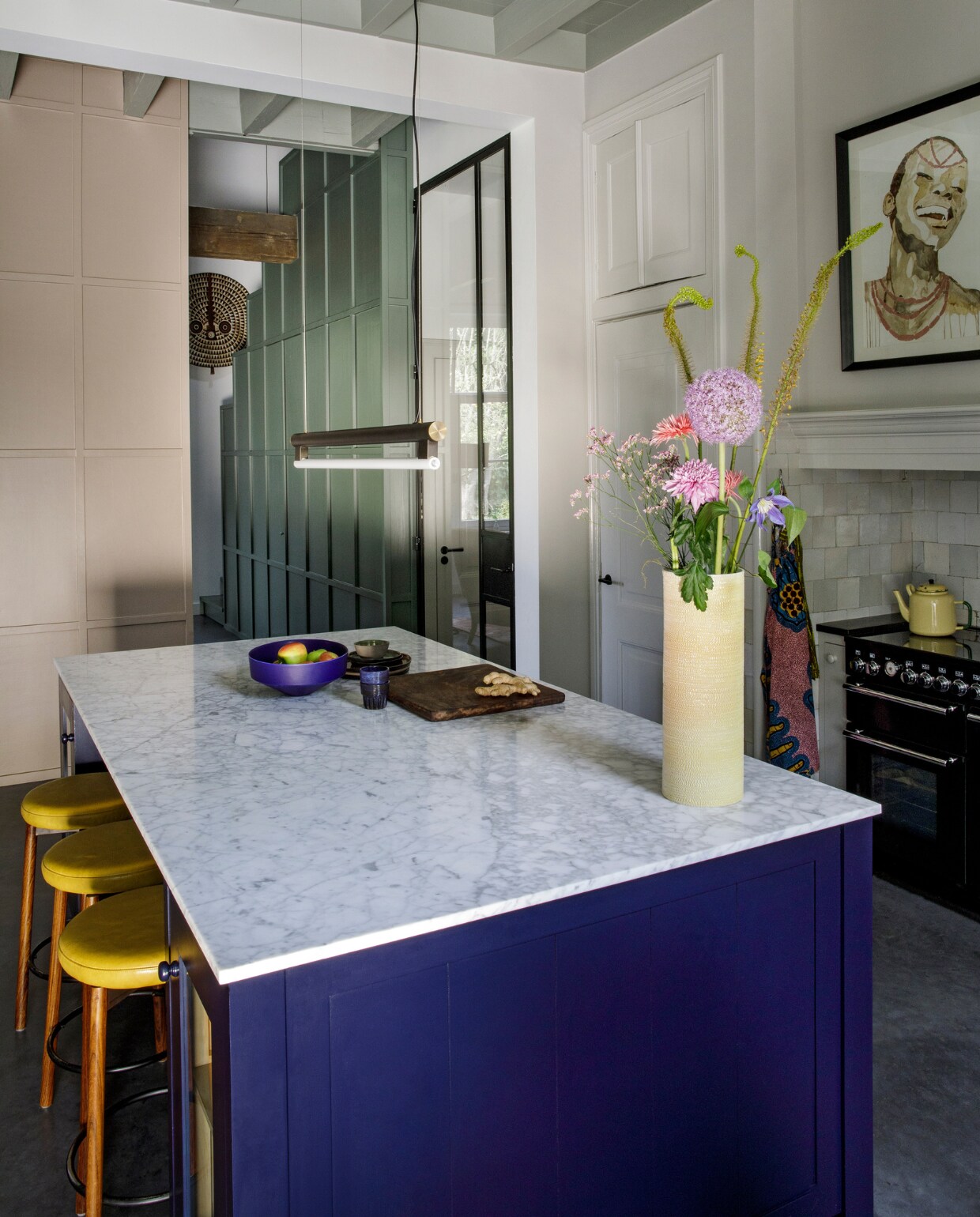 Keukenontwerp Mirte, gebouwd door Martens &amp; Dochters. Marmeren blad Revy Stone. Krukken Morentz, lamp Frama, vaas Studio Truly Truly, fruitschaal Geert Lap, aardewerk Claudy Jongstra, blauwe mokjes Mella. Fornuis Falcon. Schilderij, houten masker, houten plank, theedoek, theepot uit Nigeria. vtwonen 10-2020 | fotografie Inga Powilleit | styling José Martens