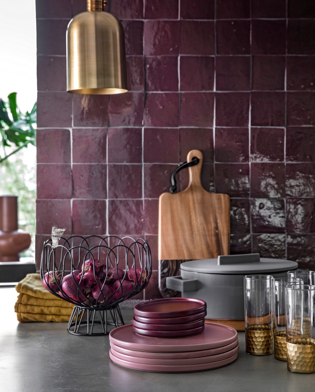 Auberginekleurige zelliges, 10x10 cm per m² € 94,50 (designtegels.nl). Bronskleurig hanglampje Aisha van Lifestyle € 69,95, draadschaal van Present Time € 17,49, grijze ovalen kookpan Terra Cotto van Eva Solo € 77,50, terraroze vaas Theseus van Urban Nature Culture € 59,95 (vtwonen.be). Plank € 47,95, ovale plank (onder de pan) € 47,95, longdrink glazen Reflexions per stuk € 10,95 (zenzahome.com). Okergele theedoeken per stuk € 3,- (hema.nl). Oudroze dinerborden per stuk € 9,99, aubergine kleurige bordjes per stuk € 4,99 (hm.com). vtwonen 02-2019 | styling Moniek Visser | fotografie Peggy Janssen