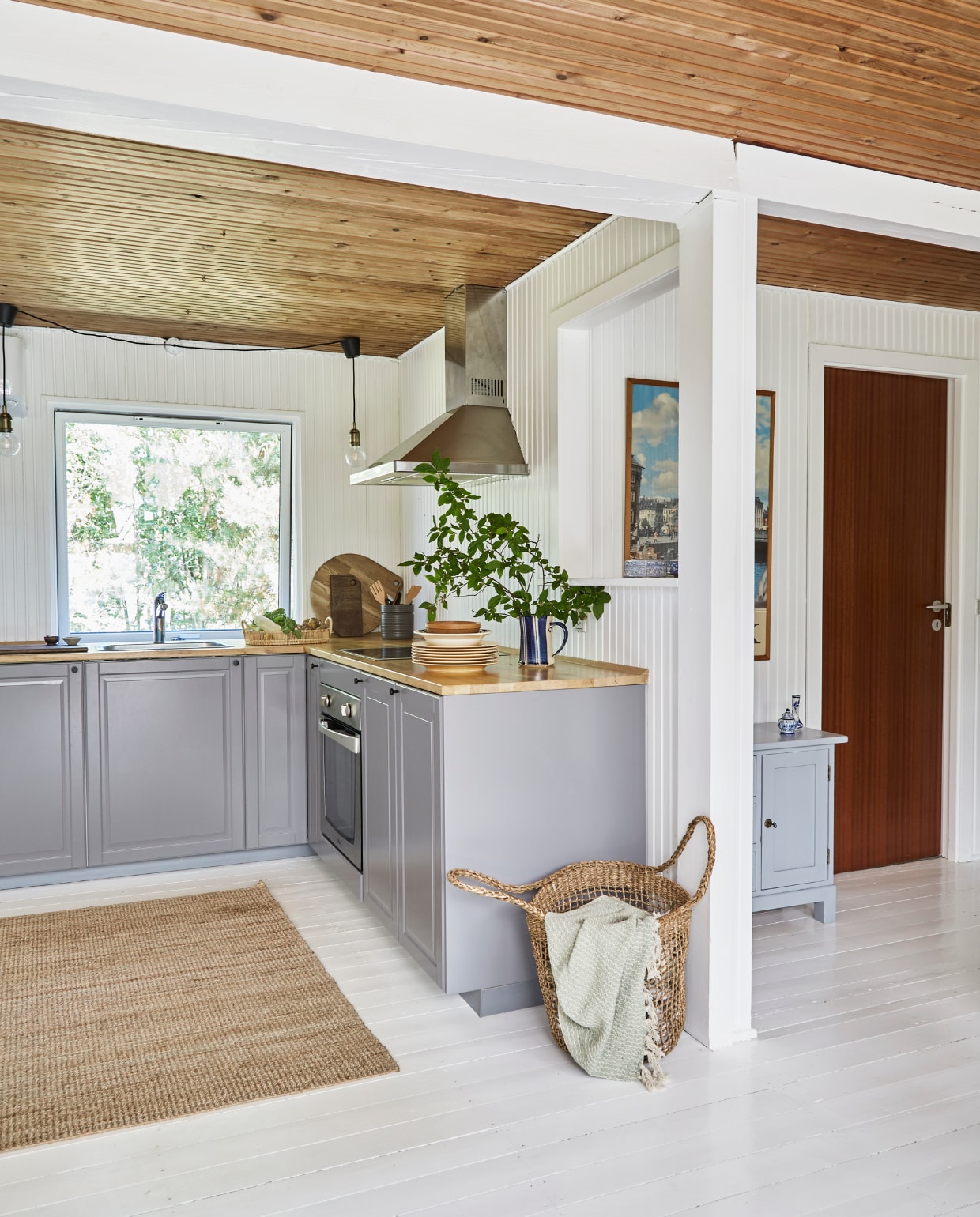 Keuken, vloerkleed en mand Ikea. Gevlochten dienblad Jysk. Pot met kookgerei Søstrene Grene. Snijplank Norwegian Wood van @sval.interior. Servies en nachtkastje rommelmarkt. Overig onbekend. vtwonen special binnenkijken 06-2023 | productie Living Inside | fotografie Anitta Behrendt | styling Rikke Graff Juel