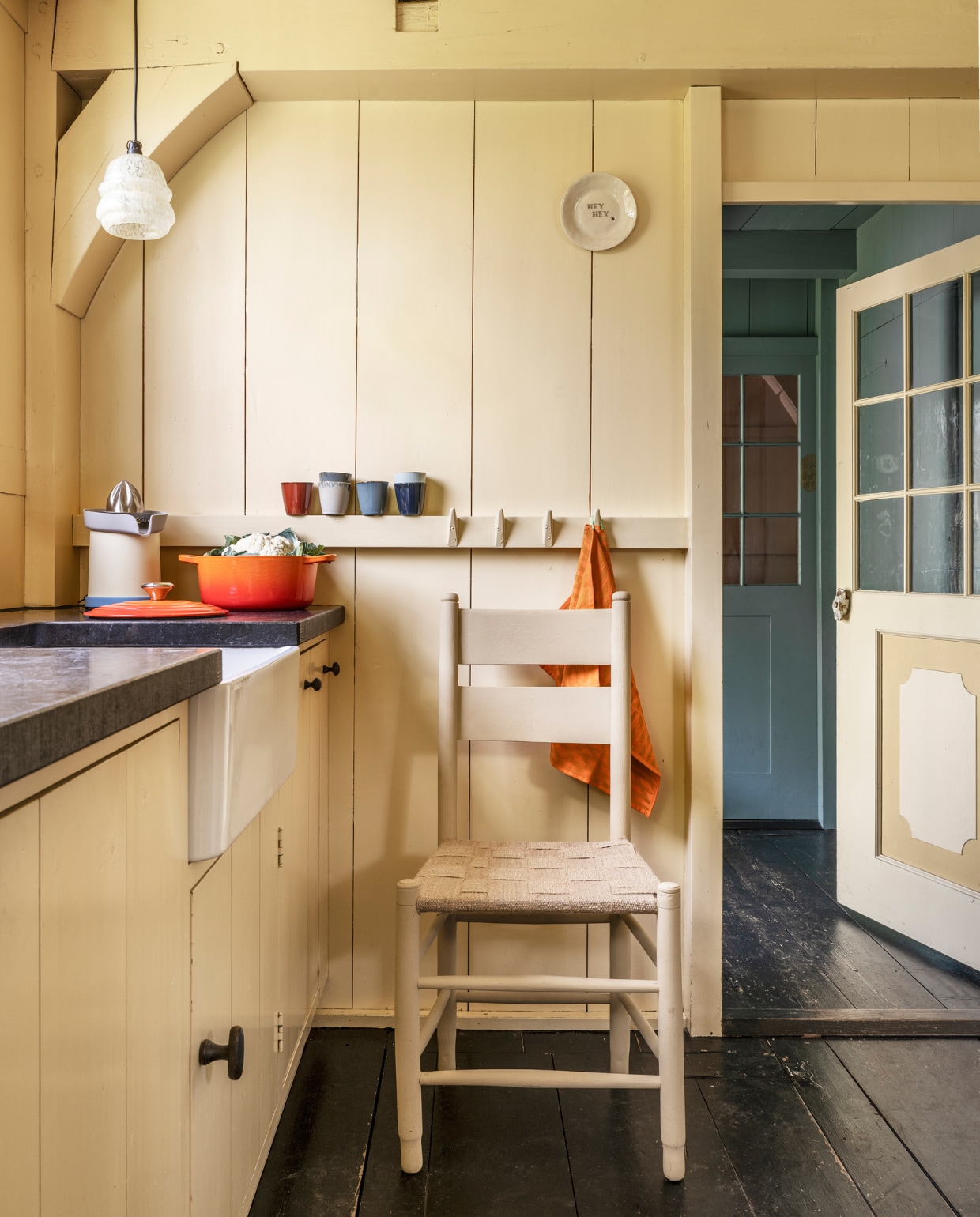 Vintage stoel € 25,- (neeflouis.nl). Krasvaste lak op waterbasis in Camel van Pure & Original, 1 liter € 77,30 (deruamsterdam.nl). Jute singelband, 7 cm breed, rol van 25 meter € 9,35 (natuurlijkjute.nl). Oranje braadpan Signature van Le Creuset € 205,-, biologisch katoenen theedoek S&B van Hay, set van 2 € 35,-, aardewerken koppen Terres de Rêves van Serax, per 6 € 49,- (vtwonen.nl/shop). Citruspers Sowden Juicer € 169,- (hay.nl). Bordje Hey hey, prijs op aanvraag (atelierroos.nl). Hanglamp privébezit. vtwonen 10-2023 | styling Marianne Luning | fotografie Stan Koolen | assistentie Rosa van Schie