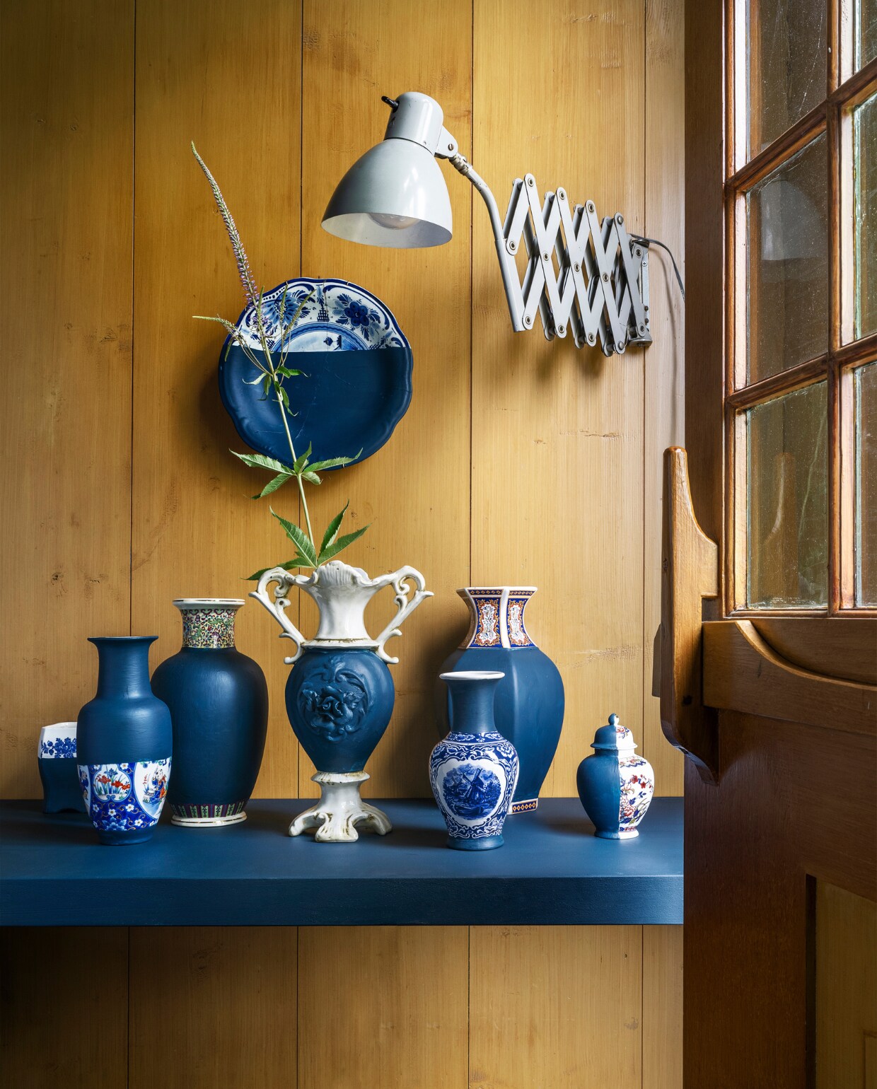 Tweedehands aardewerk en porselein, per stuk vanaf € 5,- (kringloopsaartje.nl). Blauwe verf Dead Flat in Hague Blue van Farrow &amp; Ball, per 0,75 liter € 52,- (deruamsterdam.nl). Vintage wandlamp € 90,- (neeflouis.nl). vtwonen 10-2023 | styling Marianne Luning | fotografie Stan Koolen | assistentie Rosa van Schie