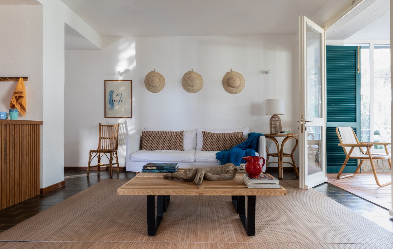 Bank en tafellamp Maisons du Monde. Kussens vintage. Bankje als salontafel Nelson van Vitra. Hoeden Trouva. De vintage bamboe stoelen stonden al in het huis. Het schilderij is een jaren 70-kunstwerk. Overig onbekend. vtwonen special binnenkijken 06-2023| productie Living Inside | fotografie Monica Spezia