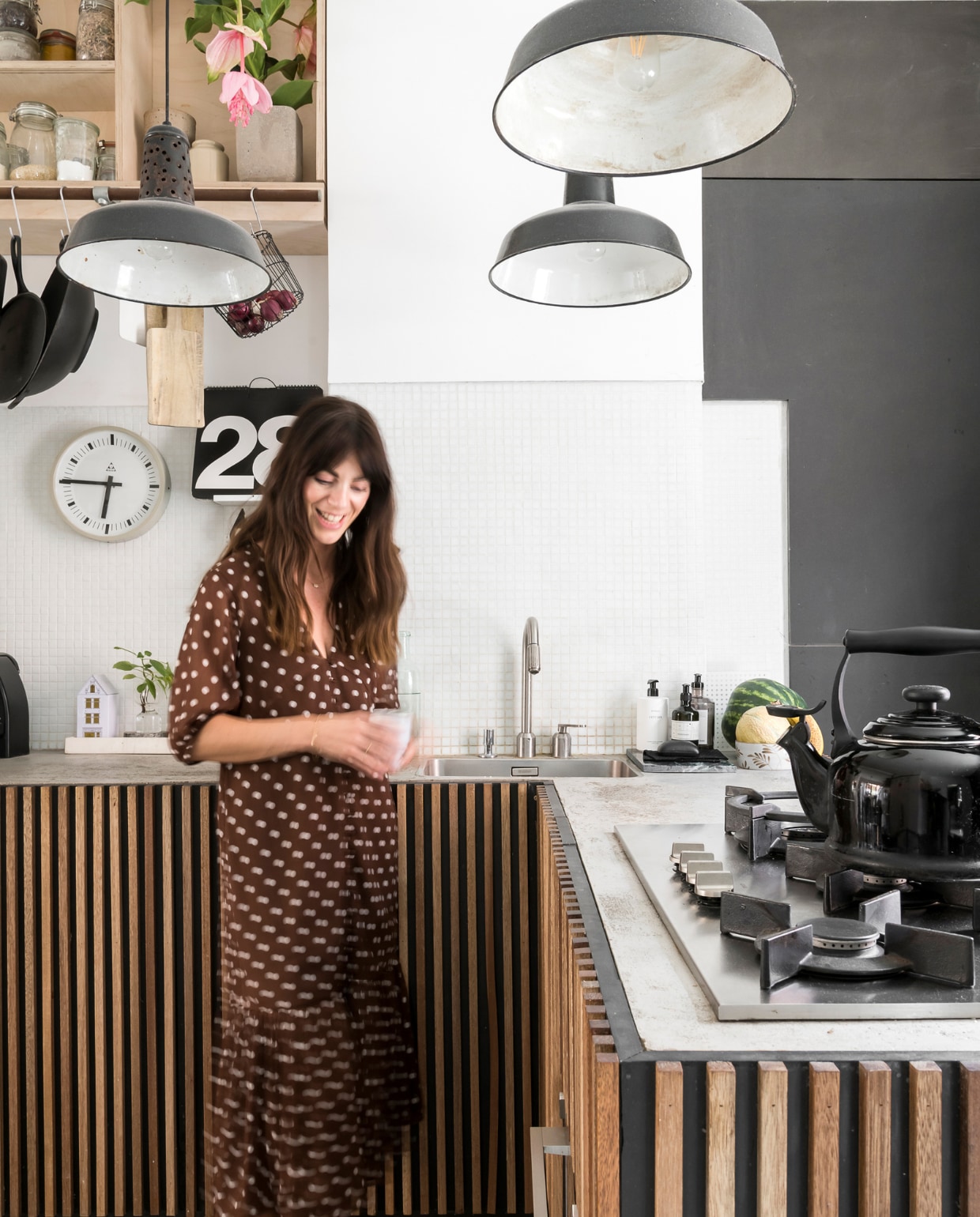 Koelkast Smeg, vintage klok van Pragotron gekocht bij Blom &amp; Blom. De keuken die William maakte is een hit op Pinterest. Het werkblad is van beton, de kastdeuren van zwarte mdf met slaglatten in meranti-hout. Lampen van een brocantemarkt in Frankrijk. vtwonen 2-2020 | Styling en Fotografie Jonah Samyn |