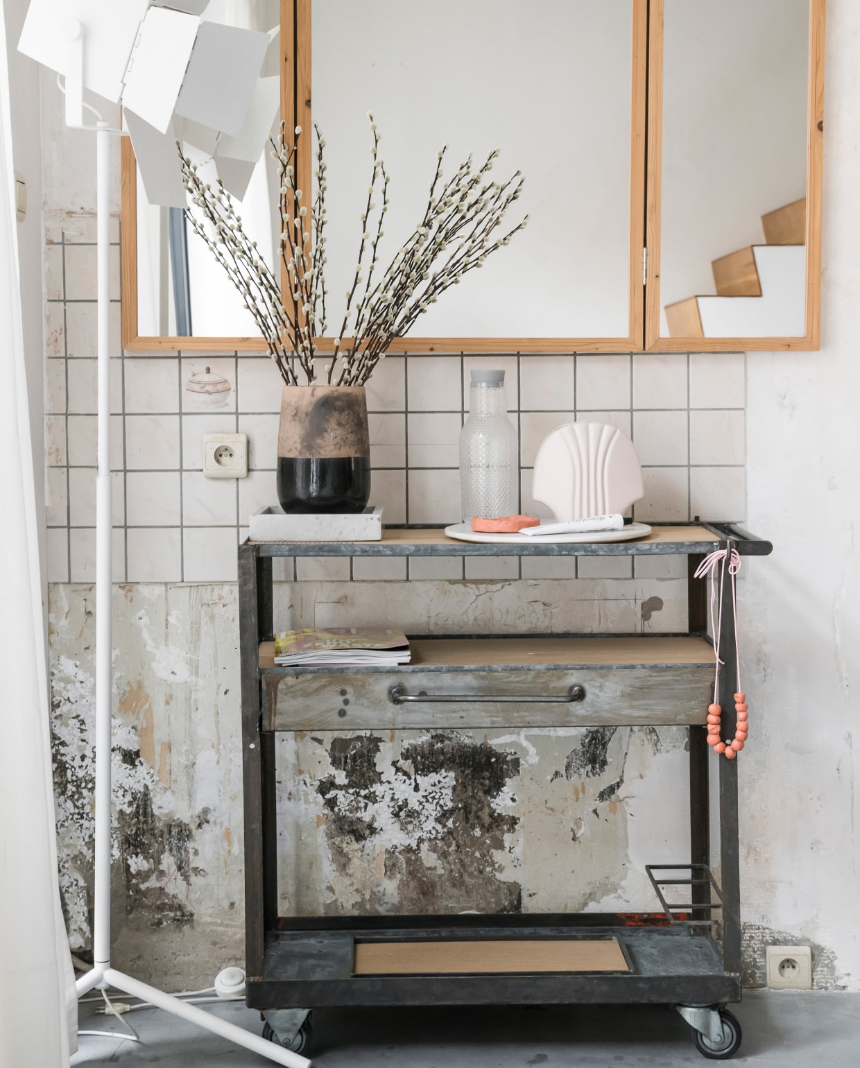 Liene en William vinden het niet nodig de sporen van de oude keuken uit te wissen. Dat geeft karakter aan hun huis. Spiegel van Piet Hein Eek, rolwagentje van Williams eigen merk Wøti. Lamp Design District, pot Mirte in Leuven. vtwonen 2-2020 | Styling en Fotografie Jonah Samyn |