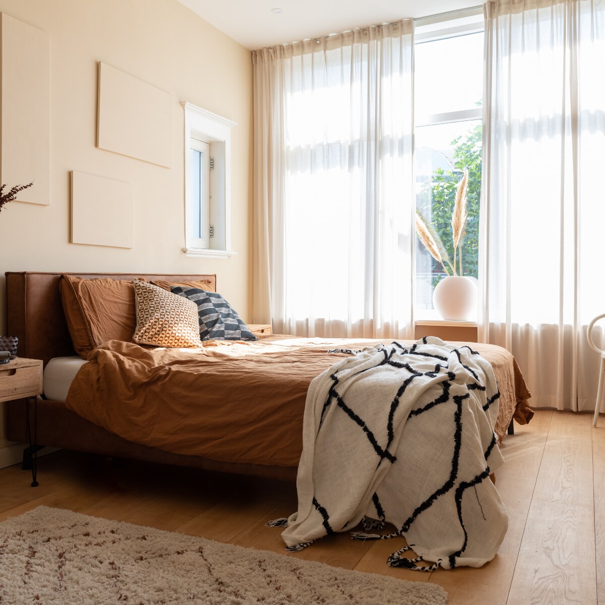 Muurkleur Medina van Histor, gordijnen Ikea. Nachtkastje, vloerkleed en bed Wehkamp Home. Vaas HKliving, glas Polspotten, tas Cotton Club. Beddengoed H&amp;M Home, sprei en kussens Karwei. Vazen Fést Amsterdam, pampaspluimen Kwantum, stoel kringloopwinkel. vtwonen 02-2023 | styling Sharon Roest | fotografie Caroline Martinot