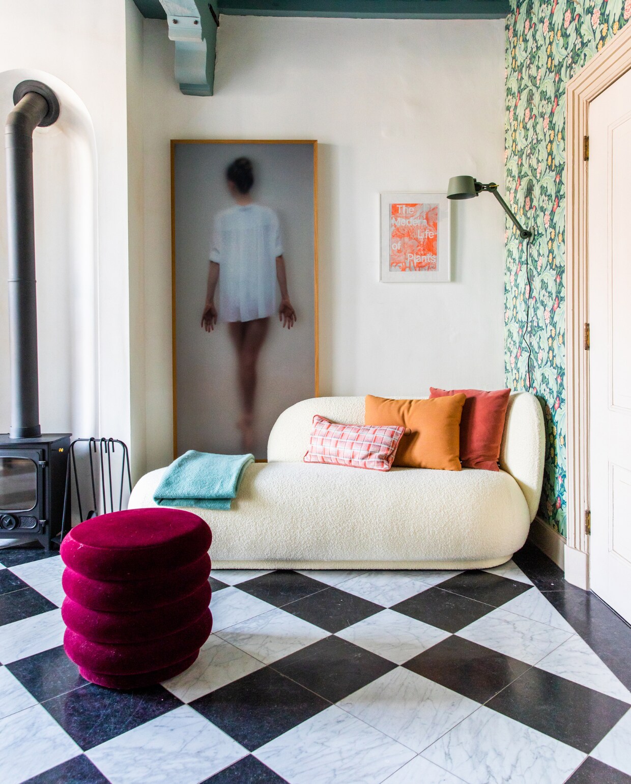 Houtkachel Dover, kunstwerk Casper Faassen, klein kunstwerk reclameposter uit Londen. Bank en poef Ferm Living. Behang Morris &amp; Co., wandlamp Tonone. Kussens Hay en zelfgemaakt. Blauwe plaid Hay, marmeren vloer origineel. Verf plafond Oval Room Blue van Farrow &amp; Ball. vtwonen 10-2023 | productie CocoFeatures | fotografie Laura Emma van Geest