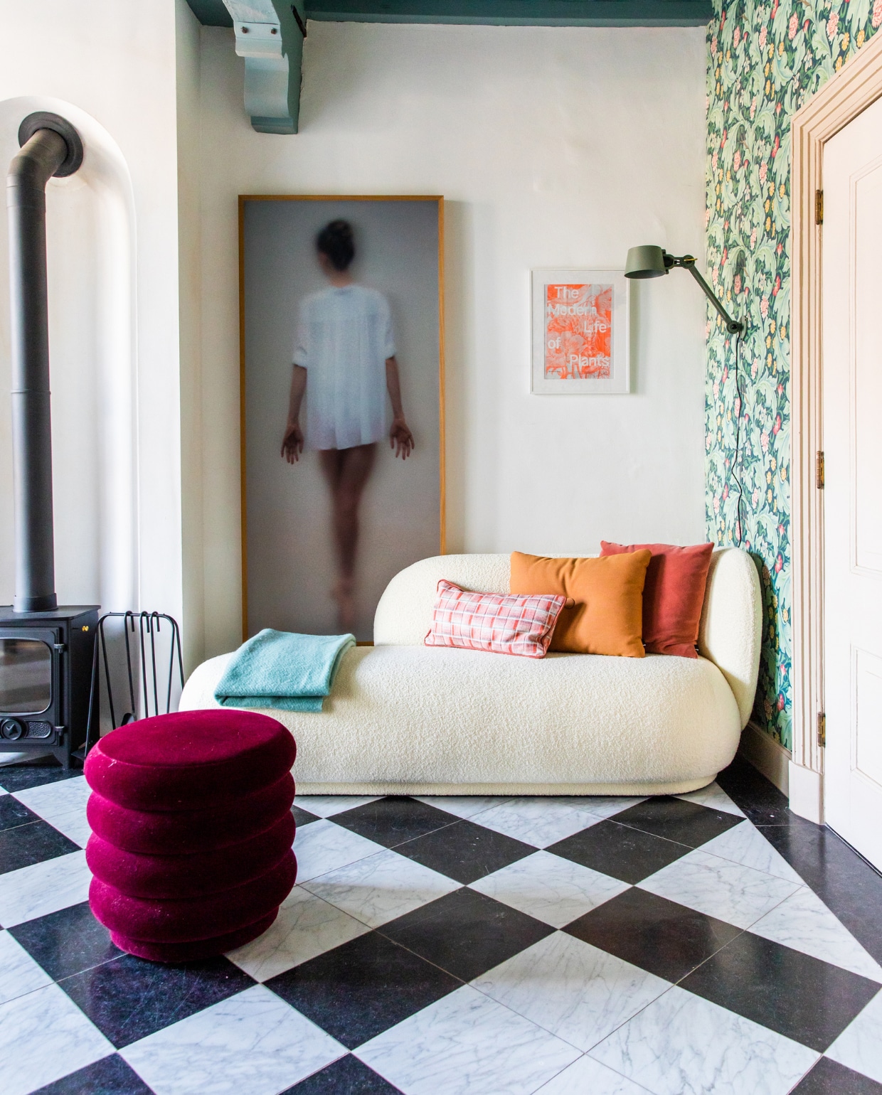 Houtkachel Dover, kunstwerk Casper Faassen, klein kunstwerk reclameposter uit Londen. Bank en poef Ferm Living. Behang Morris &amp; Co., wandlamp Tonone. Kussens Hay en zelfgemaakt. Blauwe plaid Hay, marmeren vloer origineel. Verf plafond Oval Room Blue van Farrow &amp; Ball. vtwonen 10-2023 | productie CocoFeatures | fotografie Laura Emma van Geest