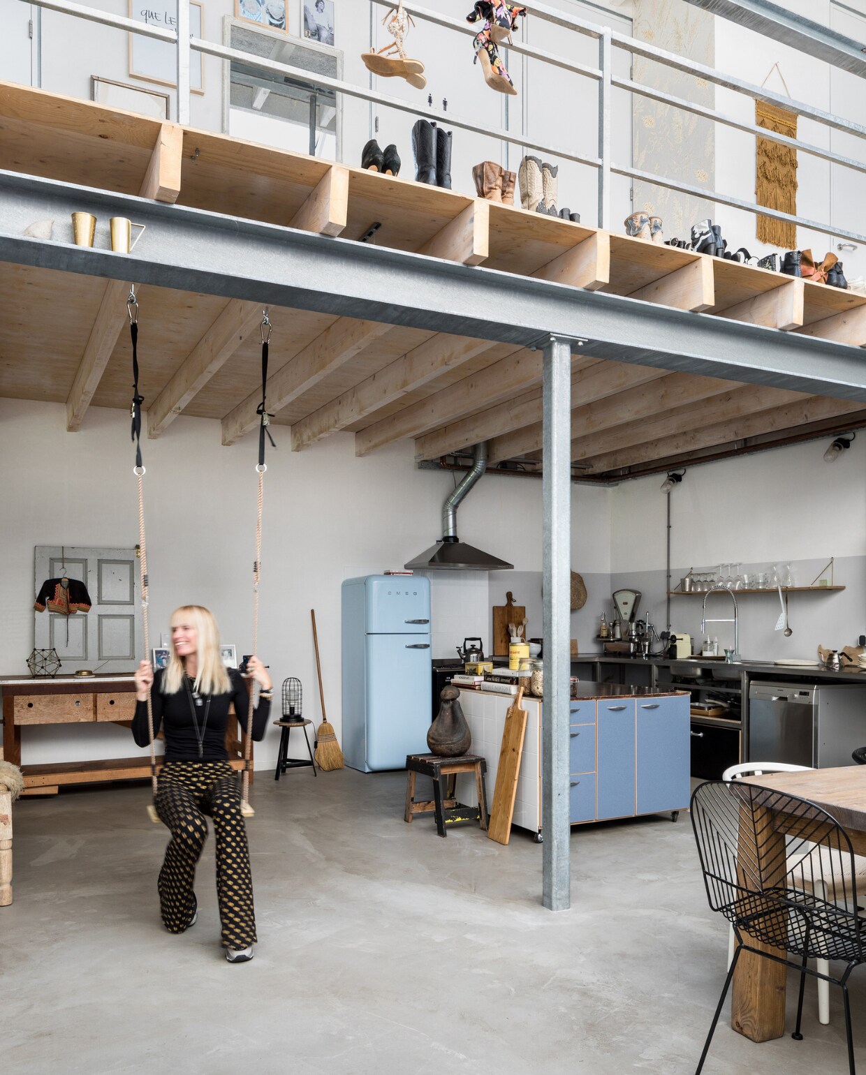 Op de vide staan Mariekes schoenen in het zicht. De vloer is van gevlinderd beton en lag er al. Draadstoel via Vintage Lab, koelkast Smeg. Het beeld op het krukje is gemaakt door Mariekes moeder, de werkbank werd door Eddy gered van de stort. De rvs horeca keuken zat er al in. vtwonen 09-2019 | styling Sabine Burkunk, Buro Binnenhuis | fotografie Hans Mossel