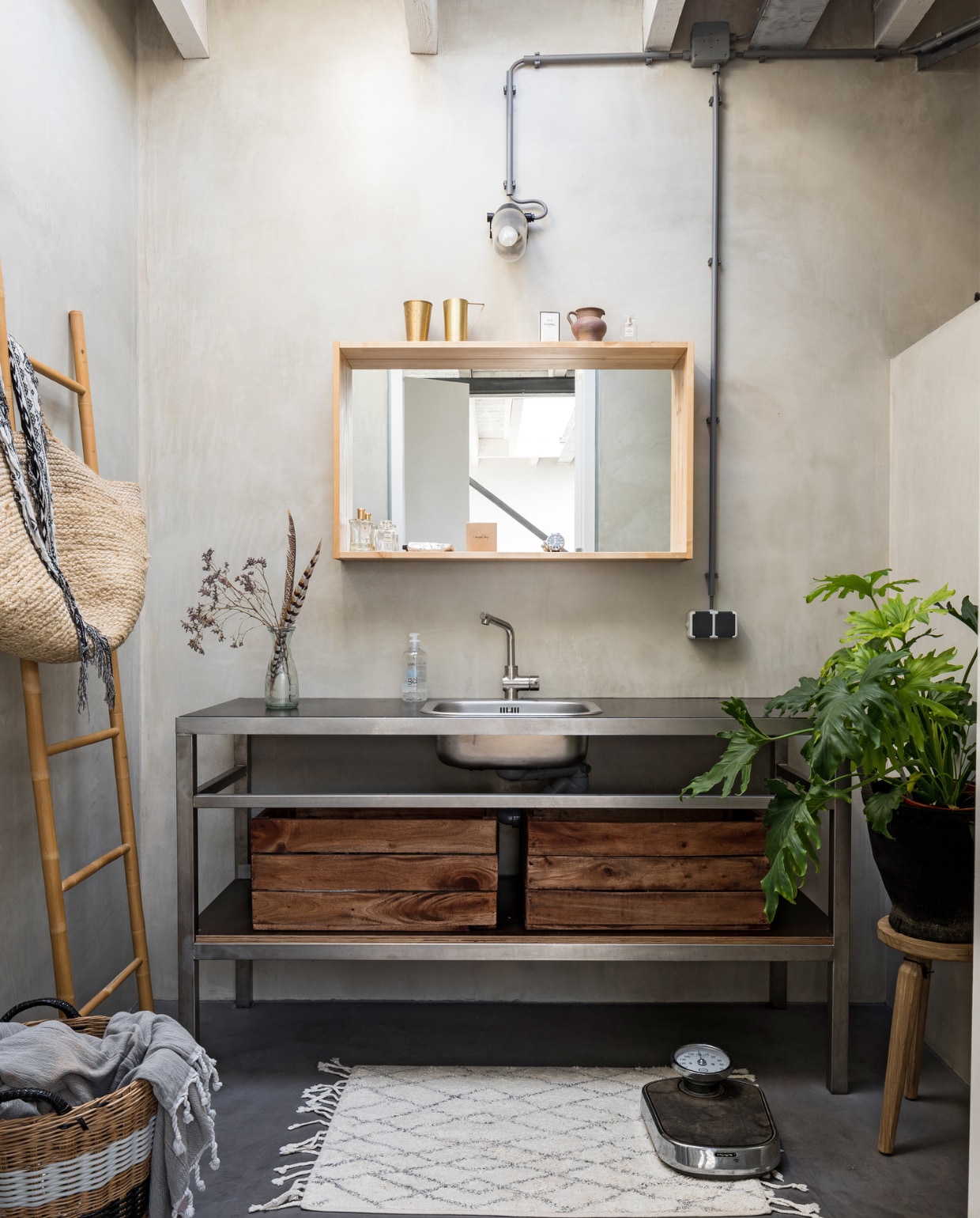 In de badkamer werden alle wanden en de vloer behandeld met beton ciré. De spiegel is van Ikea, het wastafelmeubel is op maat gemaakt van rvs. Houten kistjes van Xenos. Badmat HK Living, weegschaal Dille &amp; Kamille, ladder Hübsch. Oude mand van Mariekes moeder gekregen, hamamdoek en tas van groothandel Tica. vtwonen 09-2019 | styling Sabine Burkunk, Buro Binnenhuis | fotografie Hans Mossel