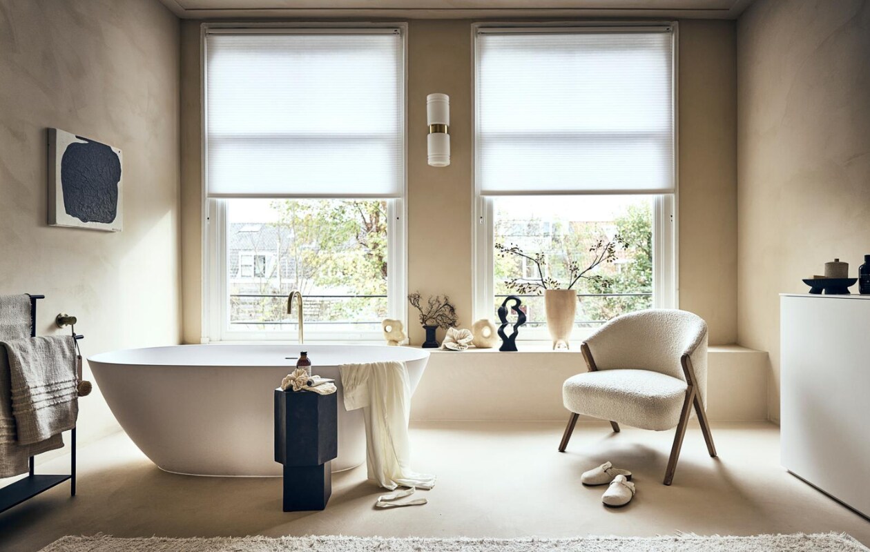 Witte stoel met houten poten en badstof bekleding € 299,-, badmat op rek € 19,99, handcrème € 15,99, vloerkleed € 219,-, sloffen € 25,99, beige bakje met deksel € 17,99, ochtendjas € 69,99, scrubhandschoen op zwart kastje, prijs op aanvraag (zarahome.com). Zwart rek van Ferm Living € 189,- (vtwonen.nl). Beige plaid € 99,-, vaasje met rond gat links € 54,95, beige vaas in het midden € 57,95, zwarte siervorm € 79,95, grote beige vaas € 89,95, borstel € 15,95 (eijerkamp.nl). Kunstwerk aan wand, prijs op aanvraag (@ansdekruyf). Papieren kunstwerk € 150,- (elsavisser.com). Zeep in fles € 18,-, losse zeep € 22,-, zeepfles op zwarte kruk, prijs op aanvraag (sukha.nl). Zwarte natuurvorm € 35,- (taxidermy.nl). Zwarte schaal op drie poten € 19,99 (hm.com). Zwarte kruk € 249,- (aedamanthony.nl). Muurverf onbekend. Overig privébezit. vtwonen 01-2023 | styling Liza Wassenaar | fotografie Sjoerd Eickmans