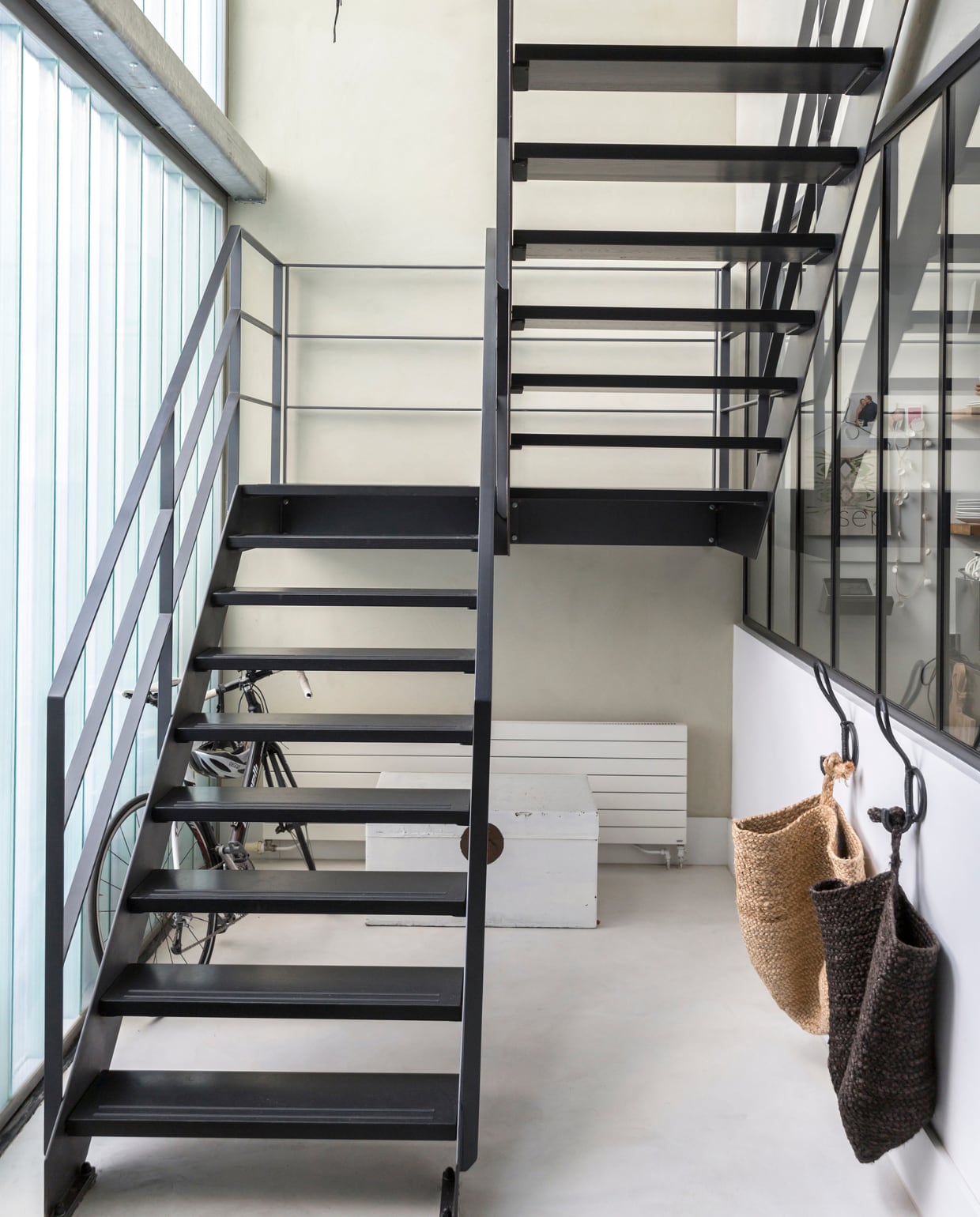 ‘De stalen trap is een idee van de architectom het modern, industrieel en tijdloos te maken en niet te rommelig.’ Hangzakken van Aai made with Love. Hanglamp van Ay Illuminate. vtwonen 11-2018 | Fotografie Margriet Hoekstra | Styling Barbara Natzijl