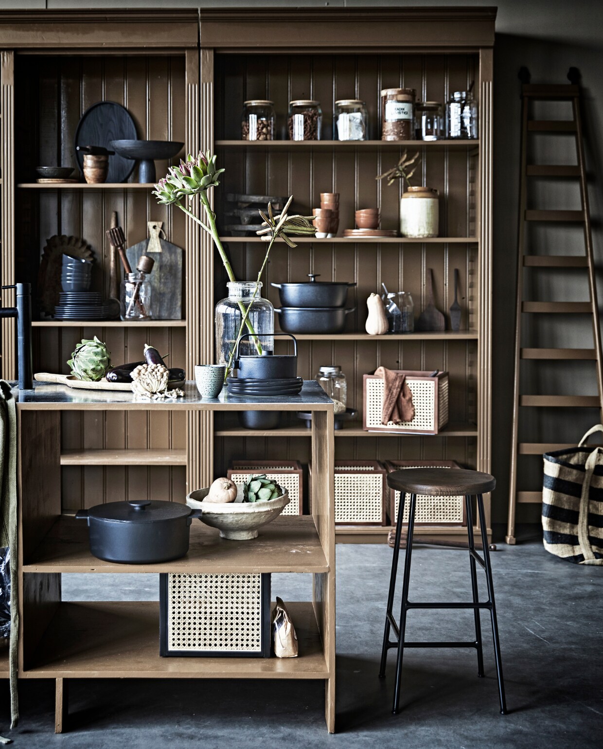 Antieke kast prijs op aanvraag (com-anders.nl). De kast is geschilderd met matte lak op waterbasis in Praline van Pure &amp; Original, per liter € 57,25 (deruamsterdam.nl). Barkruk van Hay € 199,-, theepot Collage van Serax € 88,-, keukengerei Pure van Serax, set van 5 € 53,-, ovaal dienblad Vincent Van Duysen van Serax € 89,-, kookpan Surf van Serax in keukeneiland, 5,5 liter € 190,-, bruin bord Urban Culture Nature, Ø 26 cm € 18,35, bruine kom Urban Culture Nature, Ø 12,5 cm € 12,75, zwart bord Urban Culture Nature, Ø 22 cm € 16,35 (vtwonen.nl). Voorraadpotten met houten deksel Ikea 365+ serie € 8,99, zwarte metalen braadpannen Vardagen vanaf € 44,95, poffertjespan Vardagen € 22,95, ronde pan met deksel Vardagen vanaf € 39,95 (ikea.nl). Grote glazen vaas € 33,50 (weldaad.com). Papier-maché schalen in zand en geel € 37,-, (nordal.eu). Rattan opbergboxen € 39,99, houten dienblad op pootjes € 29,90 (hm.com). Muurverf Mire van vtwonen, per liter € 18,99,  houten dienblad in kast € 55,25, (vtwonen.nl). Overig privébezit. vtwonen 11-2020 | styling Cleo Scheulderman | fotografie Jeroen van der Spek