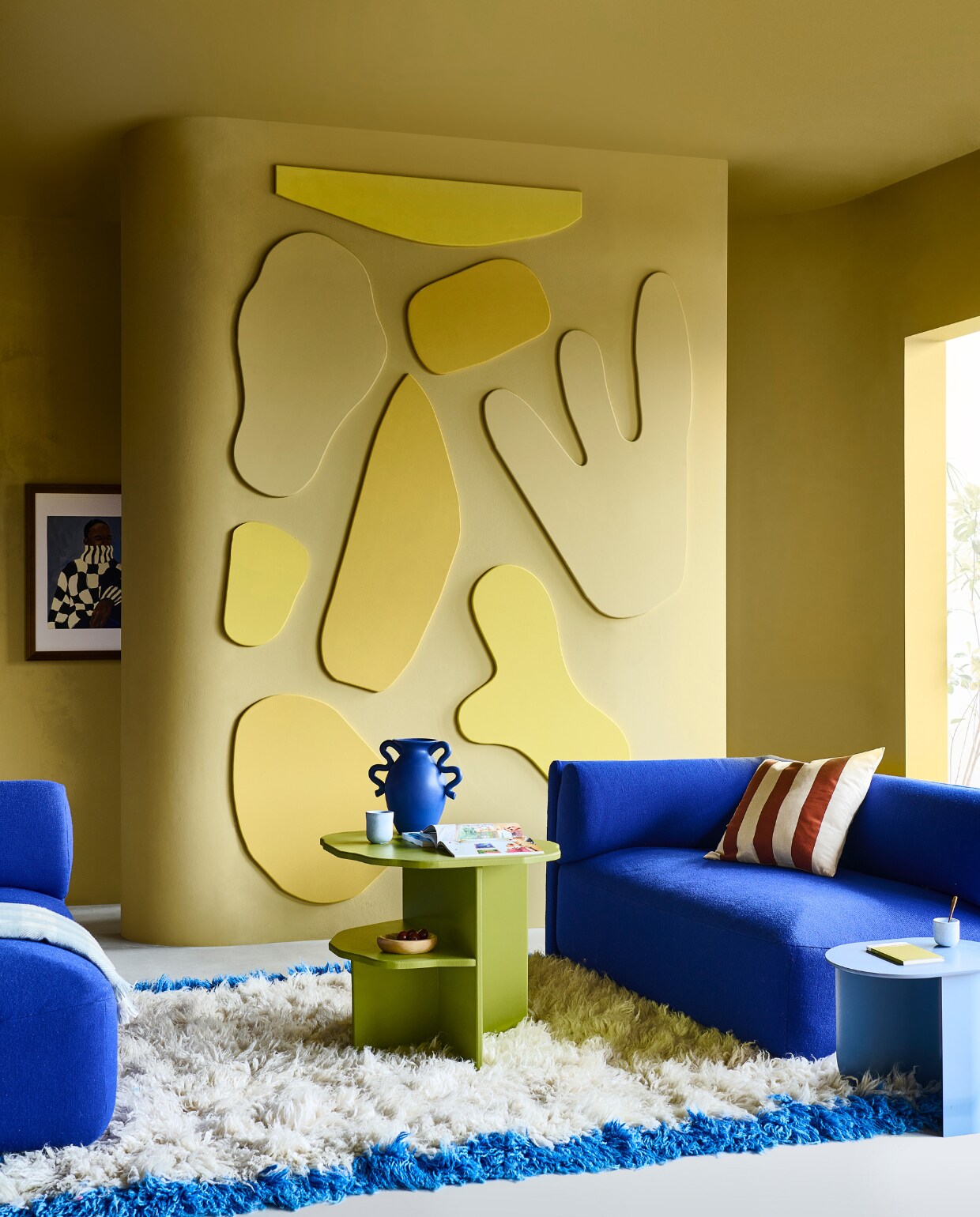 Muurverf Oak Apple no.63, lakverf voor panelen: Indian Yellow, Light Gold en Oak Apple (littlegreene.nl). Bank Bolster in stof Hallingdal 65-753 € 2798,-, bijzettafel Plateau in Pigeon Blue, hout en metaal € 249,- (festamsterdam.com). Hoogpolig vloerkleed, 280x170 cm € 1295,-, glazen blauwe pilaar, 28x28x90 cm (bxdxh) € 325,- (hkliving.com). Vaas van Ferm Living € 99,- (vtwonen.be/shop). Linnen kussenhoezen per stuk € 12,99, geblokte plaid, 130x170 cm € 29,99, lichtblauwe espressomok € 4,99, lichtblauwe keramieken beker € 9,99, houten schaaltje € 9,99 (hm.com). Poster Check van Hanna Peterson, 50x70 cm € 89,- (theposterclub.com). Overig privébezit. vtwonen special DIY 07-2023 | styling Sanne Ketelaar | fotografie Sjoerd Eickmans