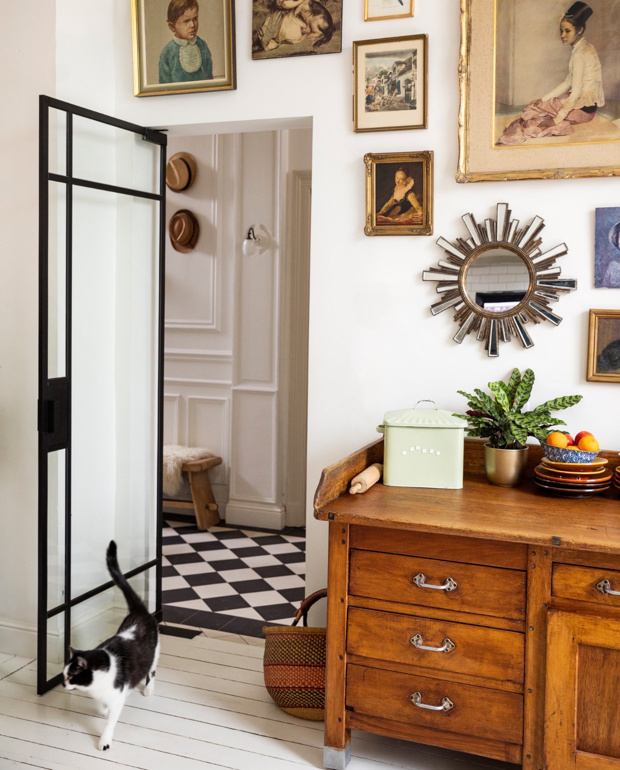 Verf muur en vloer Ral 9010, vloertegels hal Villeroy &amp; Boch. Bank Polspotten, schapenvacht Ikea, wandlamp ’t Glashuys. Lijsten kringloopwinkels en rommelmarkten, spiegel brocante, keukenblok/oud bakkersmeubel Woontheater. Mand markt, blik souvenir, plant en pot Van Uytsel, servies Marokkaanse winkel. Overig onbekend. vtwonen 10-2023 | styling Ilona Jongepier | fotografie Dana van Leeuwen