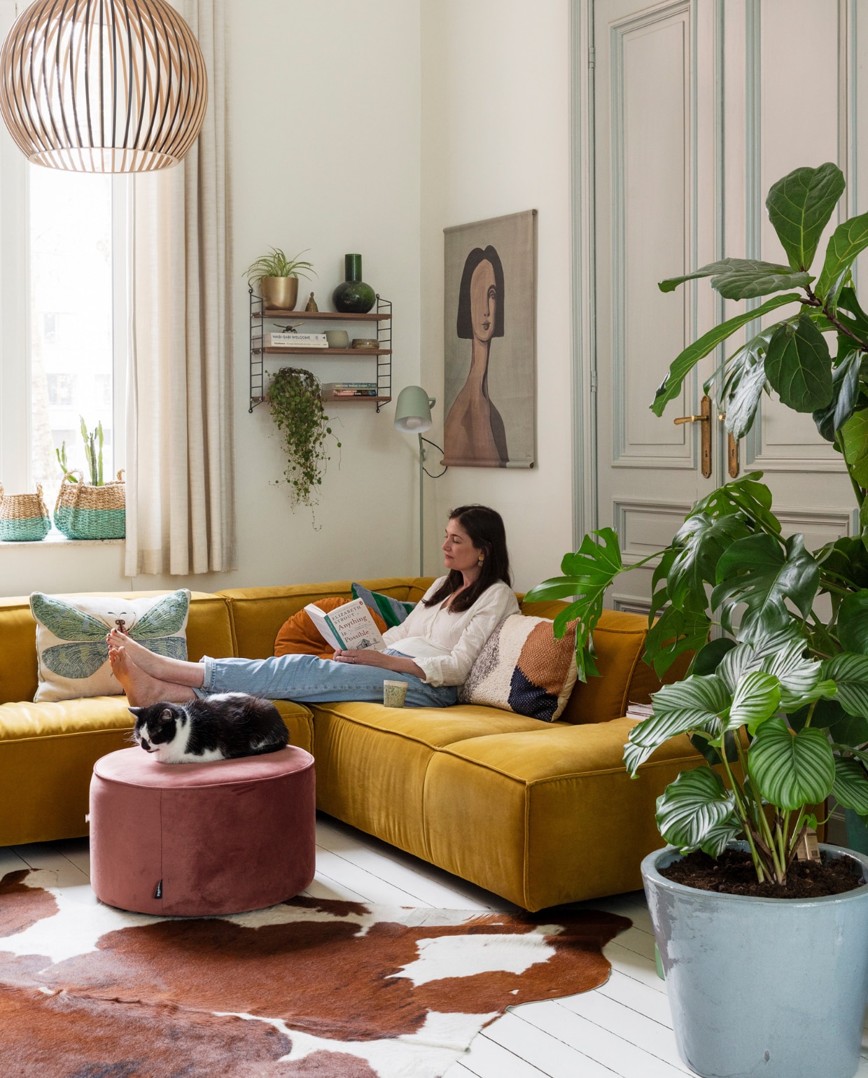 Verf muur en vloer Ral 9010, verf deuren Light Blue van Farrow &amp; Ball. Gordijnen op maat laten maken, hanglamp Octo van Secto. Manden Hema en Maisons du Monde. Wandrek String, potten en planten Van Uytsel. Vaas, schilderij en kussen met bruine vlakken HKliving. Vloerlamp Lau van Zuiver, bank Dunbar van Fést. Kussens vlinder en streep Sissy-Boy, rond kussen Ikea, poef Sara van Woood, vloerkleed koevel van de markt. vtwonen 10-2023 | styling Ilona Jongepier | fotografie Dana van Leeuwen