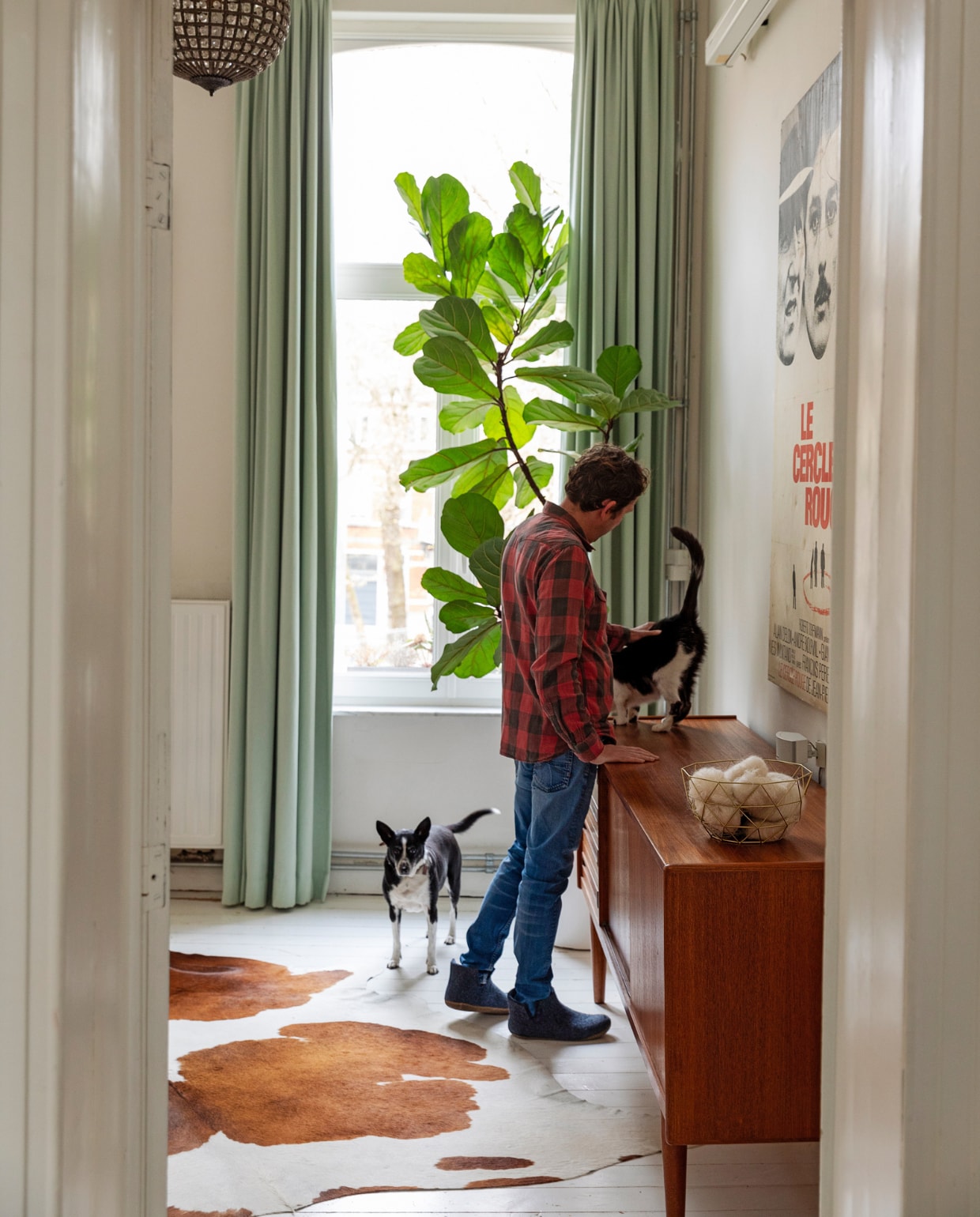 Hanglamp markt Marollen, gordijnen Hema, plant Aldi. Poster oude filmposter uit Frankrijk op doek laten spannen. Vloerkleed koevel van de markt, dressoir Møbelfabrik. Overig onbekend. vtwonen 10-2023 | styling Ilona Jongepier | fotografie Dana van Leeuwen