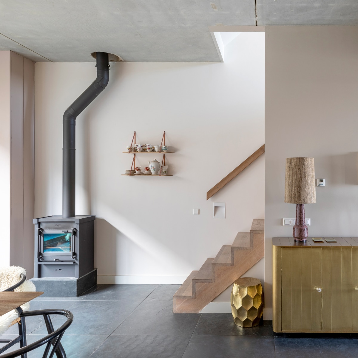 Flexa Creations muurverf bij de kachel Wit Sesam, boven de kast Worthy Clay (flexa.nl). Vierkant kunstwerk van Luitzen Zandbergen, prijs op aanvraag (instagram.com/luitzenz). Lampenvoet van HKliving € 159,-, lampenkap van HKliving € 109,95 (vtwonen.nl). Wandplanken, per stuk € 39,95, plankdragers, per stuk € 32,95 (handlesandmore.nl). Kommen, set van 3 € 19,95 (eijerkamp.nl). Vazen van Light &amp; Living, per stuk € 14,95 (dutchhomelabel.nl). Bloemen, prijs op aanvraag (bloemenweelde-amsterdam.nl). Overig privébezit. vtwonen Weer Verliefd op je Huis seizoen 16 aflevering 8 | fotografie Mrgriet Hoekstra | styling Eva van de Ven