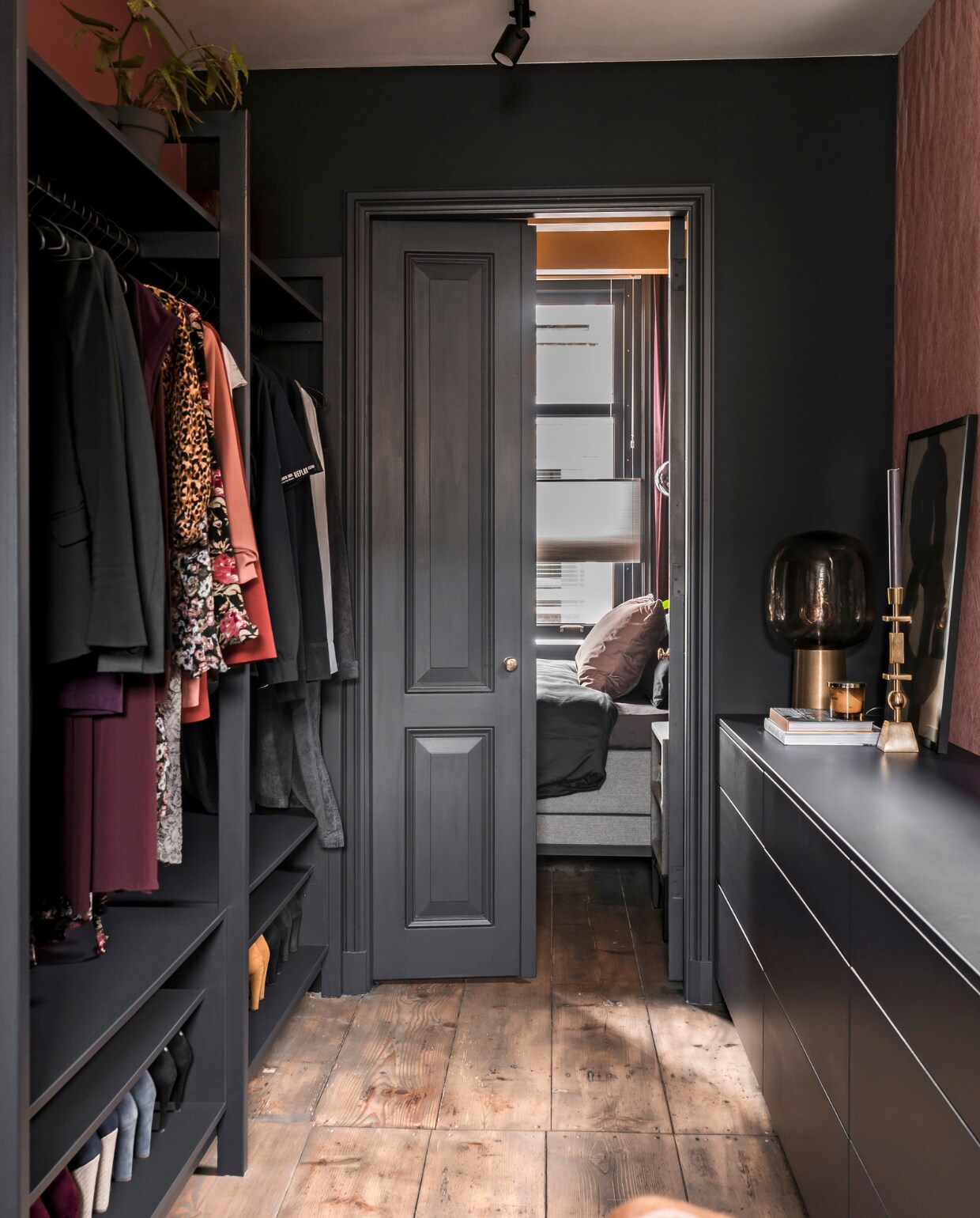 Inloopgarderobe met speciaal ontworpen kasten en paneeldeuren, geverfd in Rijkszwartgrijs van Sikkens. Tafellamp Note House. Kandelaar Westwing. Grenen vloerdelen opgeschuurd en afgewerkt met antracietkleurige olie. vtwonen special binnenkijken 06-2022 | producie CoCo Features | fotografie Muk van Lil, Chiela van Meerwijk