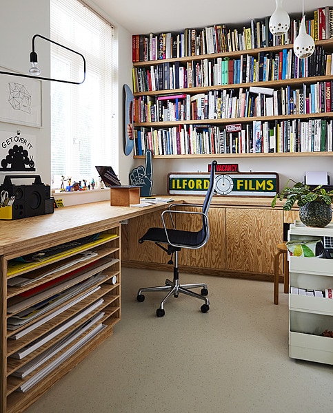 Op maat gemaakt bureau met posterlade en boekenplanken Schriever Interieurbouw, speaker Ikea x Teenage Engineering, illustratie Get over it Tim Lahan, illustratie zwart-wit Rafaël Rozendaal, lamp X+L. Schuimvinger, kalebas hanglampen en klok vintage. Ontwerp skateboard Ewoudt Boonstra, stalen kast Joe Colombo, pot Loods 5, kruk Artek, vloer Marmoleum Cocoa van Forbo. vtwonen 11-2023 | styling Mariella Kallenberg | fotografie René Mesman