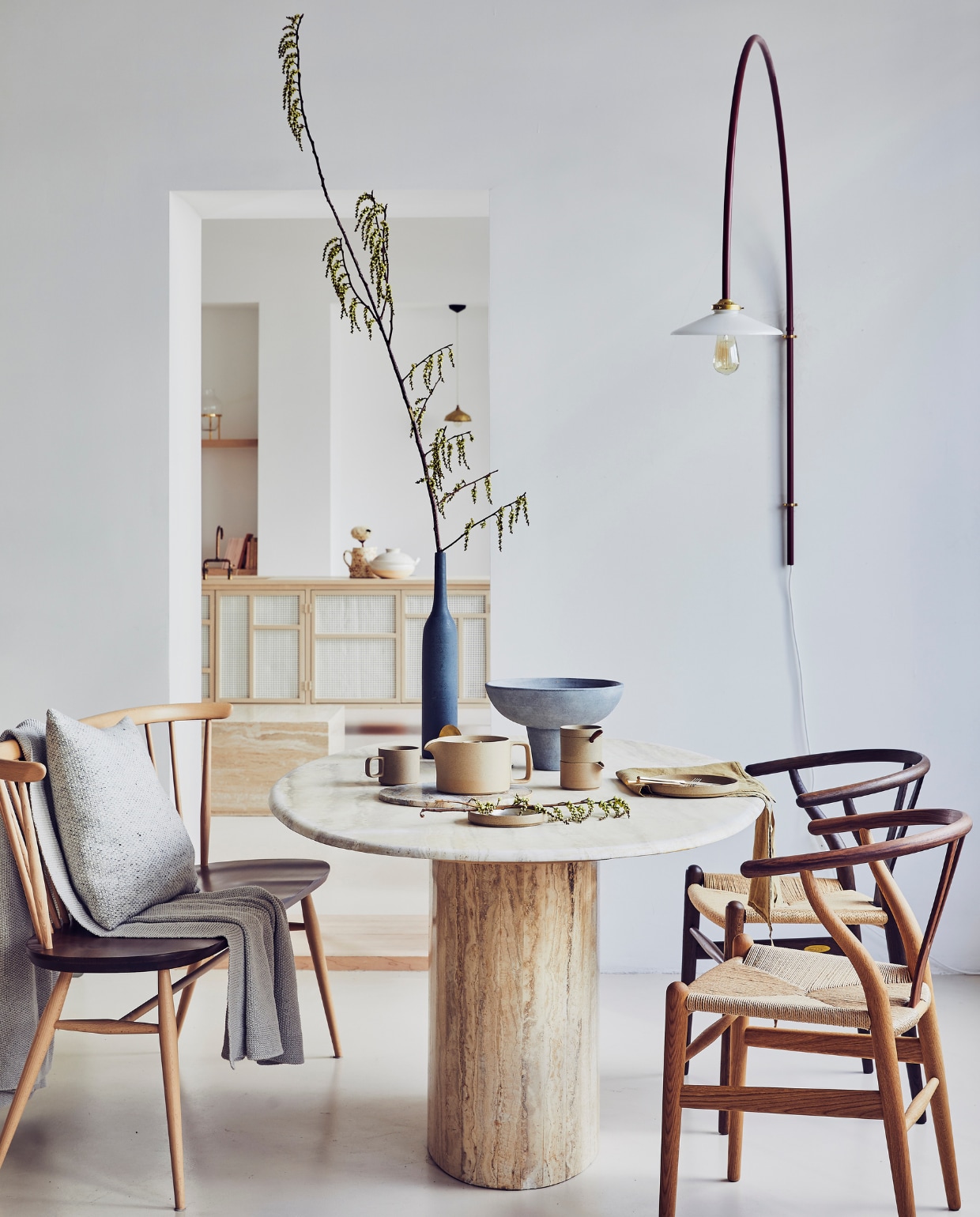 Vintage tafel van travertin € 2700,-, Wishbone chair stoelen van Carl Hansen, van gecertificeerd hout, per stuk vanaf € 499,-, theepot van Hasami Porcelain € 69,-, suikerpot en melkkannetje van Hasami Porcelain € 39,-, bord van Hasami Porcelain € 43,-, beker van Hasami Porcelain € 26,-, groene linnen theedoek van Linge Particulier € 19,95, bankje van Ercol € 1290,-, wollen kussen van Mourne € 135,-, wandlamp van Muller van Severen € 720,- (pantoufle-design.nl). Merino wollen plaid € 139,- (bymolle.com). Grijze schaal op voet € 47,- (101cph.com). Fles van keramiek € 35,99 (zarahome.com). vtwonen 05-2019 | styling Cleo Scheulderman | fotografie Jeroen van der Spek