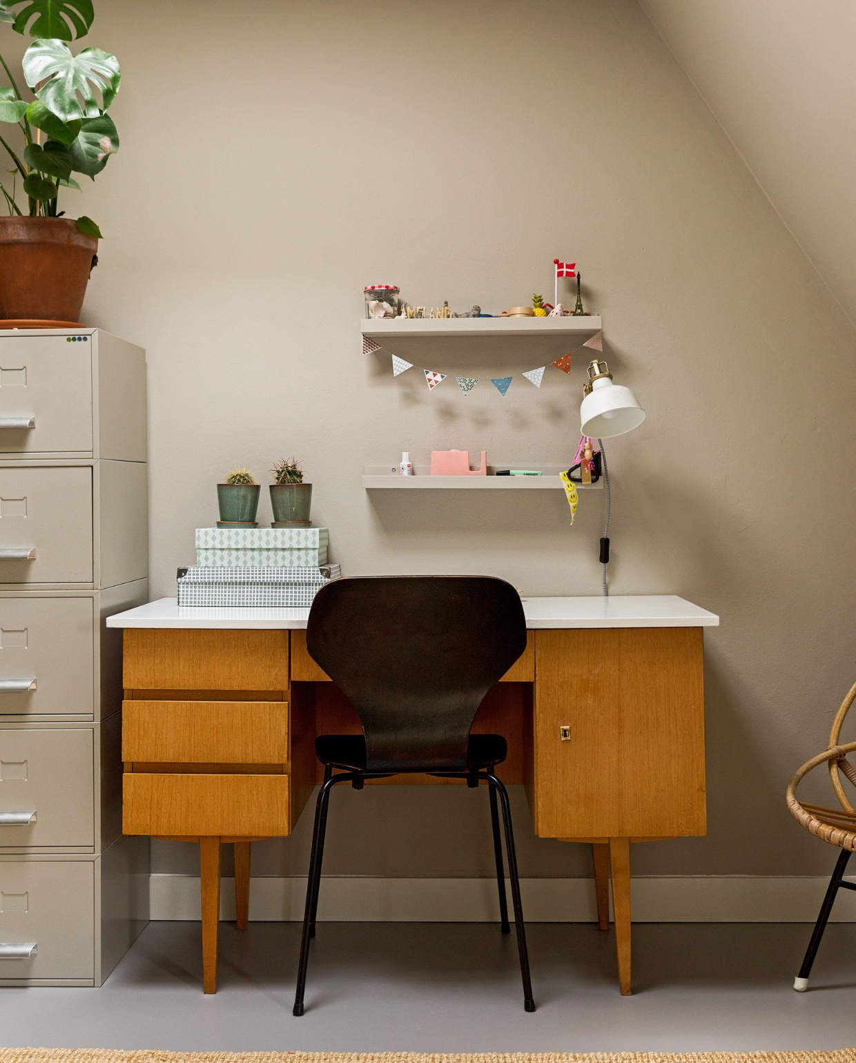 Muurkleur RAL 7044. Bureau, kast en rieten stoel Marktplaats. Stoel vintage. Vloerkleed, wandplank en lamp Ikea. Dozen, plant Nørd Conceptstore. Op de vloer ligt linoleum. vtwonen 10-2022 | Styling Ilona Jongepier | Fotografie Dana van Leeuwen