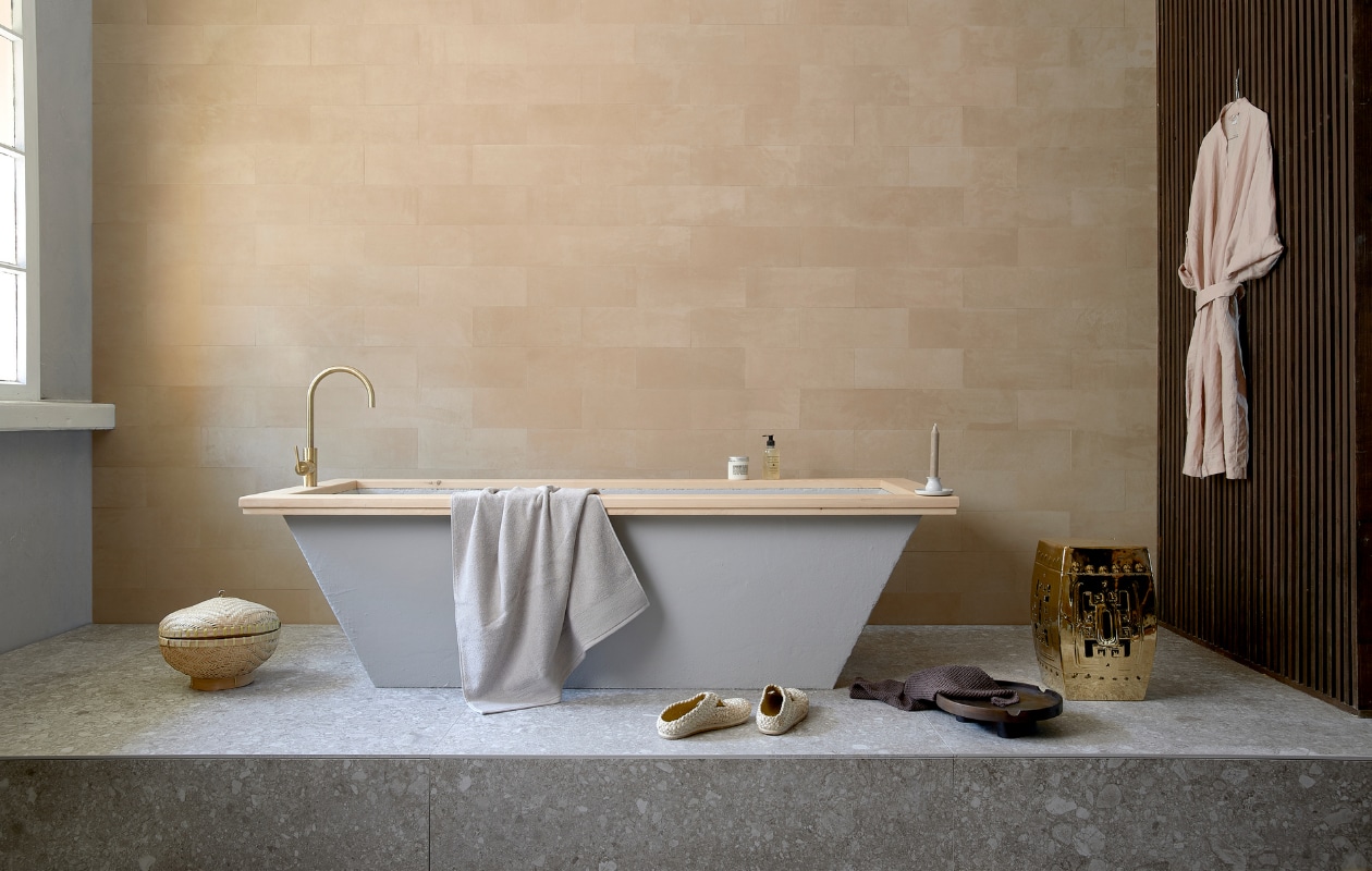 Leren wandtegels uit de Colorado collectie, kleur 3901 desert, als afgebeeld € 4500,- (ohmannleather.com). Podiumvloer met vloer-en wandtegel Composite Light Grey van vtwonen, 120x120 cm per m² € 79,95 (vtwonentegels.nl). Bad betonlook met houten rand, op maat gemaakt, prijs op aanvraag, lattenwand, prijs op aanvraag (com-anders.nl). Kraan Grip van vtwonen € 596,- (vtwonen.be). Ecru handdoek € 14,99, schaal € 24,99, bruine handdoek € 5,99, linnen ochtendjas € 39,99 (hm.com). Schoenen € 105,- (sukha.nl). Kruk Temple € 386,50 (polspotten.nl). Rieten mand € 22,50 (loods5.nl). Overig privébezit. vtwonen 10-2020 | styling Fietje Bruijn | fotografie Dennis Brandsma
