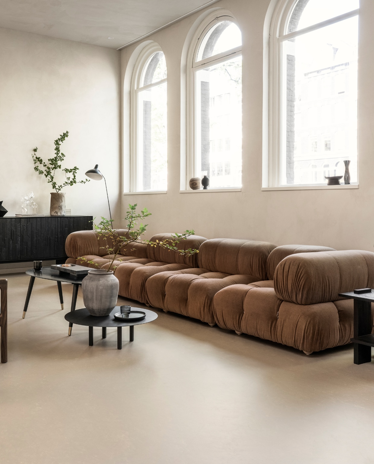 Marmoleum vloer in Kwarts, 200 cm breed, per m² € 50,40. M.m.v. homestede.nl (elementenbank), vtwonen.nl/shop (metalen tafellamp van HKliving, ronde salontafel van Serax), ethnicraft.com (fauteuils), zarahome.com (ovale salontafel, stenen vaas, zwarte vaas, zwart houten bord), 101cph.com (stenen dienblad), @ansdekruyf (kunstwerken). Overig privébezit. vtwonen 10-2023 | styling Sanne Ketelaar | fotografie Stan Koolen
