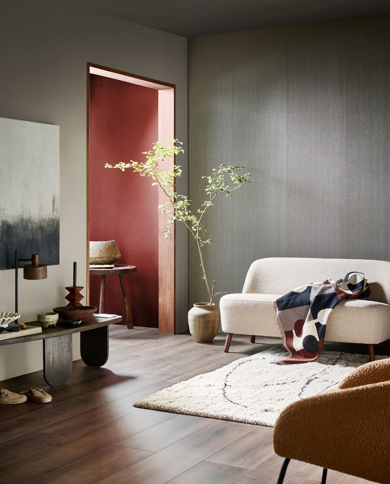 Evc-vloer Rye, incl. ondervloer, lamel 129x24,6 cm, inhoud per pak 2,54 m², per m² € 52,99, muurverf rond deur Mirre en in hal Terra, vanaf 1 liter € 27,99, behang Herringbone Soil Gold, 53 cm x 10 m (bxl), per rol € 32,99, metalen tafellamp Woody, 30x16x51cm (bxdxh), excl. lichtbron € 79,99, kunststof vloerkleed Doodle, 200x290 cm € 279,-. M.m.v. neeflouis.nl (bijzettafel), zarahome.com (pot, stenen schaal, houten kandelaar, sloffen), karwei.nl (fauteuil Ditte, bank Roan), hm.com (plaid, witte schaal). Overig privébezit. vtwonen 11-2023 | productie tanja Saarberg | styling Sanne Ketelaar | fotografie Sjoerd Eickmans