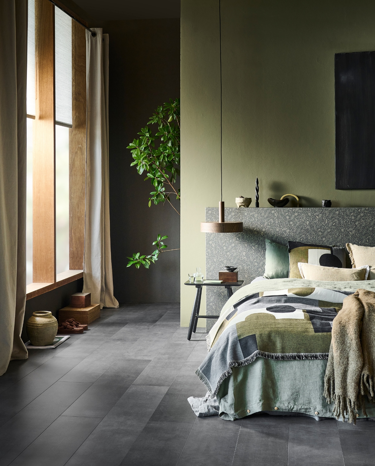 Evc-vloer Granite, incl. ondervloer, lamel 129x24,6 cm, inhoud per pak 2,54 m², per m² € 52,99, muurverf achtermuur Soil en achter bed Fennel, vanaf 1 liter € 27,99, rolgordijn Pebble in lichtgrijs, lichtdoorlatend, 90x190 cm (bxh) € 78,99, gordijn Denim Flax, lichtdoorlatend met ring, 140x270 cm (bxh) € 62,99, metalen hanglamp Woody, 35x8 cm (Øxh), excl. lichtbron € 99,-, behang op hoofdbord Twigs Soil Gold, 53 cm x 10 m (bxl), per rol € 32,99. M.m.v. bymolle.com (dekbedovertrek Olive, kussenslopen Olive), vtwonen.nl/shop (zwarte houten kruk van Villa Collection), hm.com (plaid met print, kussen met print, sandalen, wollen plaid), zarahome.com (houten doos met metalen deksel, stenen vaas, karaf, zwarte gedraaide kaars, linnen kussenhoes, notitieboeken). Overig privébezit. vtwonen 11-2023 | productie tanja Saarberg | styling Sanne Ketelaar | fotografie Sjoerd Eickmans