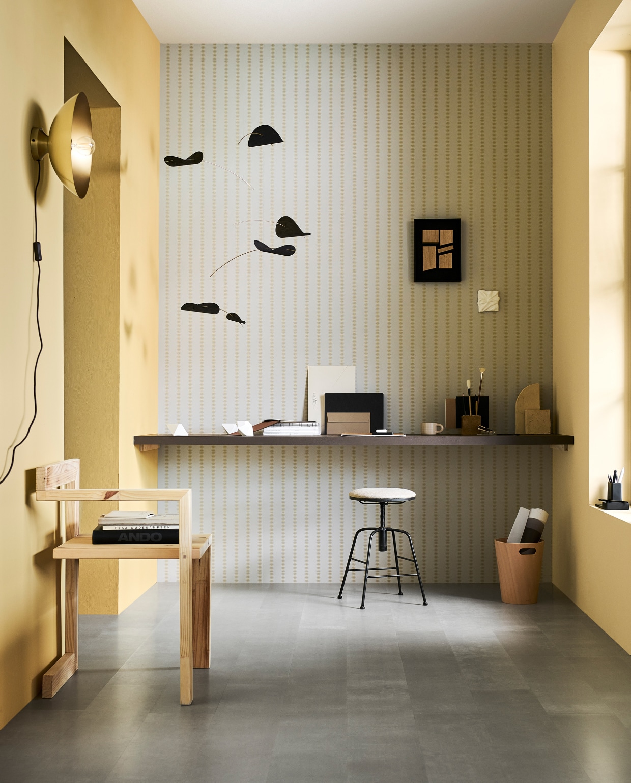 Laminaat vloer XL Pitch, met groef, lamel 138x32,6x0,8 cm, inhoud per pak 2,25 m², per m² € 32,99, muurverf Almond, vanaf 1 liter € 27,99, lakverf voor bureau Warm Brown, vanaf 500 ml € 27,99, behang Gold Diamond Flax, 53 cm x 10 m (bxl), per rol € 32,99, metalen wandlamp Disk in antiek brons, 33x15 cm (Øxh), excl. lichtbron € 49,99.M.m.v. vtwonen.nl/shop (houten papierbak van Umbra, stenen sculpturen van Ferm Living, zwarte pennenbak van Zone Denmark, stenen pennenhouder van Ferm Living), deensedingen.nl (mobile), hm.com (mok), zarahome.com (stalen kruk, envelop). Overig privébezit. vtwonen 11-2023 | productie tanja Saarberg | styling Sanne Ketelaar | fotografie Sjoerd Eickmans