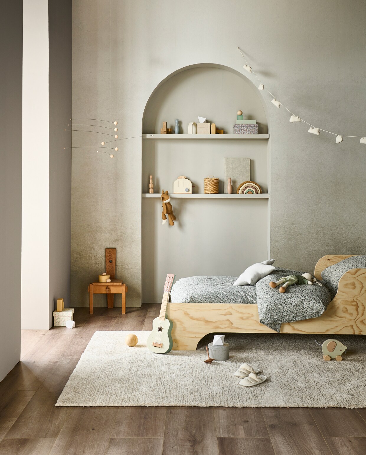 Evc-vloer Barley, incl. ondervloer, lamel 129x24,6 cm, inhoud per pak 2,54 m², per m² € 52,99, muurverf linkerwand Mire en in boog Light Grey, vanaf 1 liter € 27,99, fotobehang achterwand Degradé in Warm Grey, 6 banen van 50x280 cm, totaal 300x280 cm (bxh) € 149,-, kunststof vloerkleed Soft Draw, 160x230 cm € 179,-.M.m.v. neeflouis.nl (kinderstoel), zarahome.com (gitaar, houten broodrooster, houten regenboog, sloffen, rieten mand, knuffel vos, knuffel haas, houten muis), deensedingen.nl (mobile), hm.com (dekbedovertrek, stervormig kussen, slingers met wolken). Stappenplan DIY kinderbed van vtwonen: go.vtwonen.nl/vt11-2023. Overig privébezit. vtwonen 11-2023 | productie tanja Saarberg | styling Sanne Ketelaar | fotografie Sjoerd Eickmans