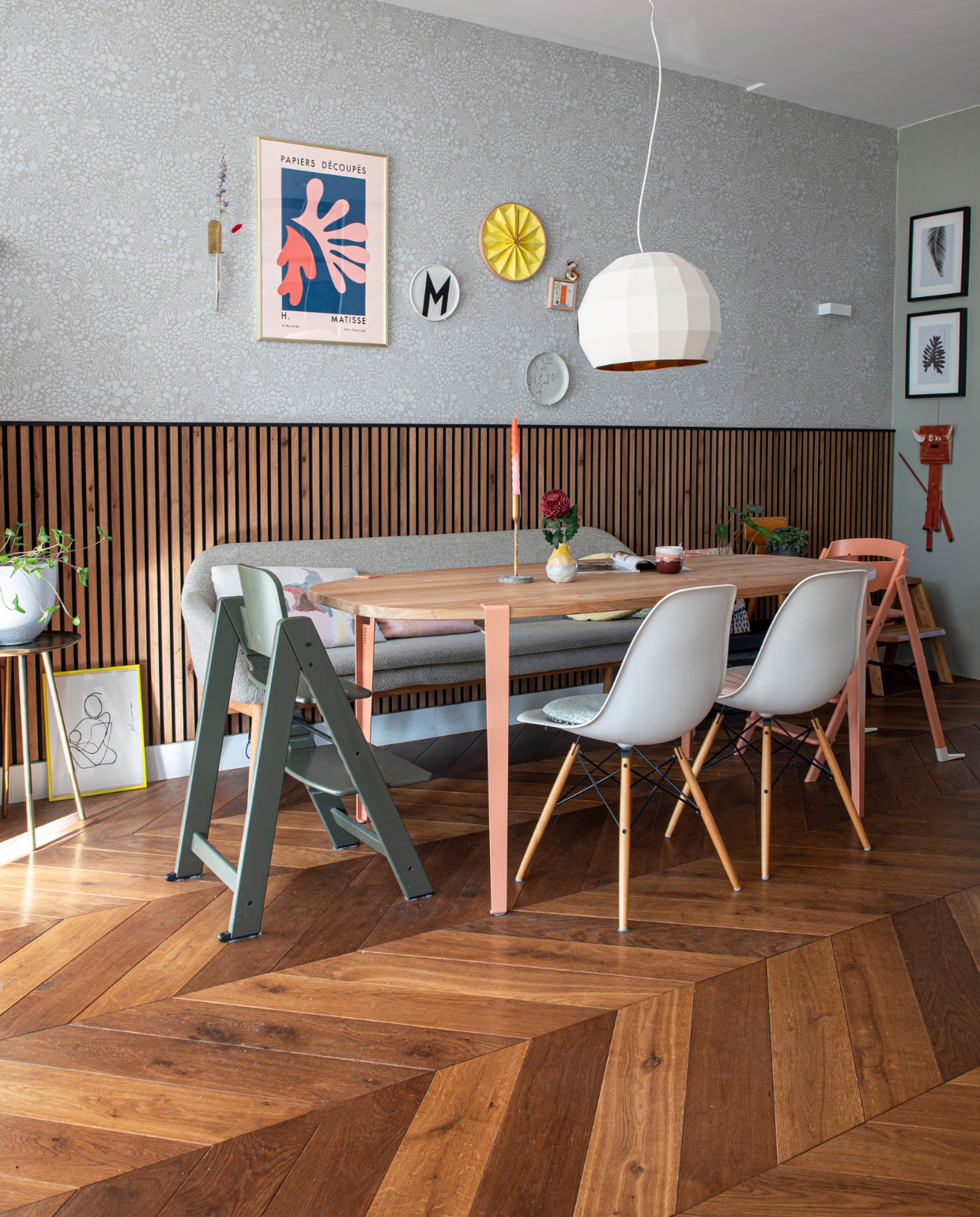 Eettafel DIY-blad met poten van Tiptoe, mok Prchtg, kandelaar Morph Design, stoelen Vitra, groene kinderstoel Kidsmill, roze kinderstoel Kaos, eetkamerbank Bolia, kussens Tom Dixon, hanglamp Marset, lambrisering Woodupp, bijzettafel Nijhof, behang Midbec, bord met letter M Design Letters, tegel Storytiles, gele klok Snowpuppe, poster Matisse van Postery, wandlamp Wever &amp; Ducré. Houten vloer Van der Heijden vloeren. Overig onbekend. vtwonen special DIY 7-2023 | fotografie Caroline Coehorst | tekst Chris Muyres