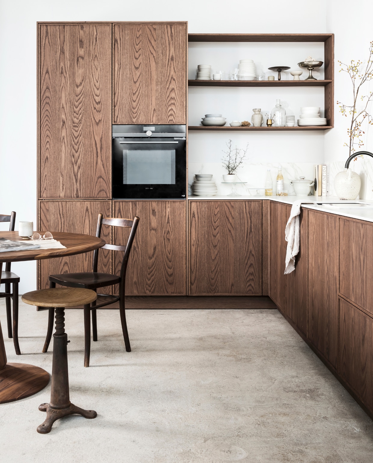 DARK OAK Prijs zoals getoond vanaf ? 17.500,- M.m.v.: mandemakers.nl, dezaakdesign.nl (tafeltje met marmeren blad, fotolijstje, rond dienblad, wit te vaas, hanglamp L amber t, stoelen en kruk), burbri.nl (koperen pannen), hm.com (linnen theedoek en schor t), villajipp.nl (af wasborstel), demachinekamer.nl (ronde walnoothouten tafel van Sav &amp; Okse), simonlevelt.nl (Slow Cof fee apparaat), kringloopwinkel (schaal op tafel), overig privbezit. vtwonen special vtverbouwen keuken 2022 | fotografie Sjoerd Eickmans, Peggy Janssen | styling Kim van Rossenberg
