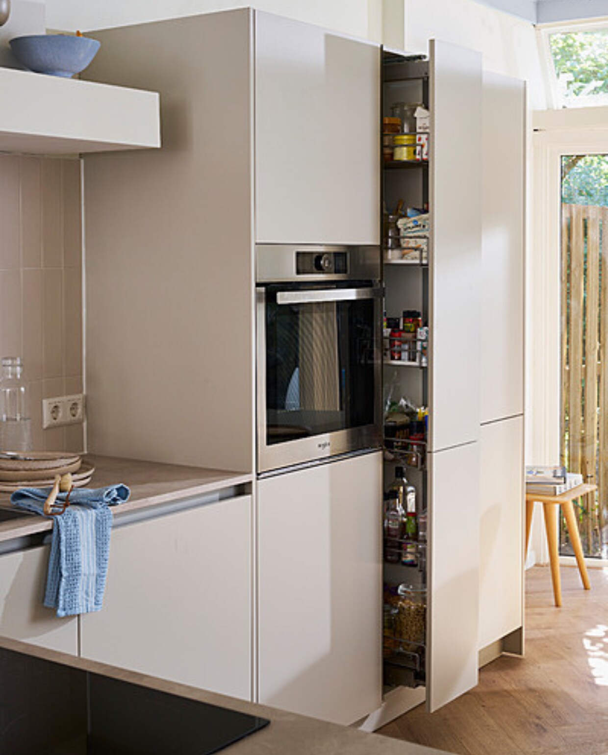 Keuken Basic Greige met diverse formaten opbergkasten, prijs op aanvraag. M.m.v. hm.com (kom, borden, theedoek, demachinekamer.nl (houten kruk). Overig privébezit. vtwonen catalogus 2023