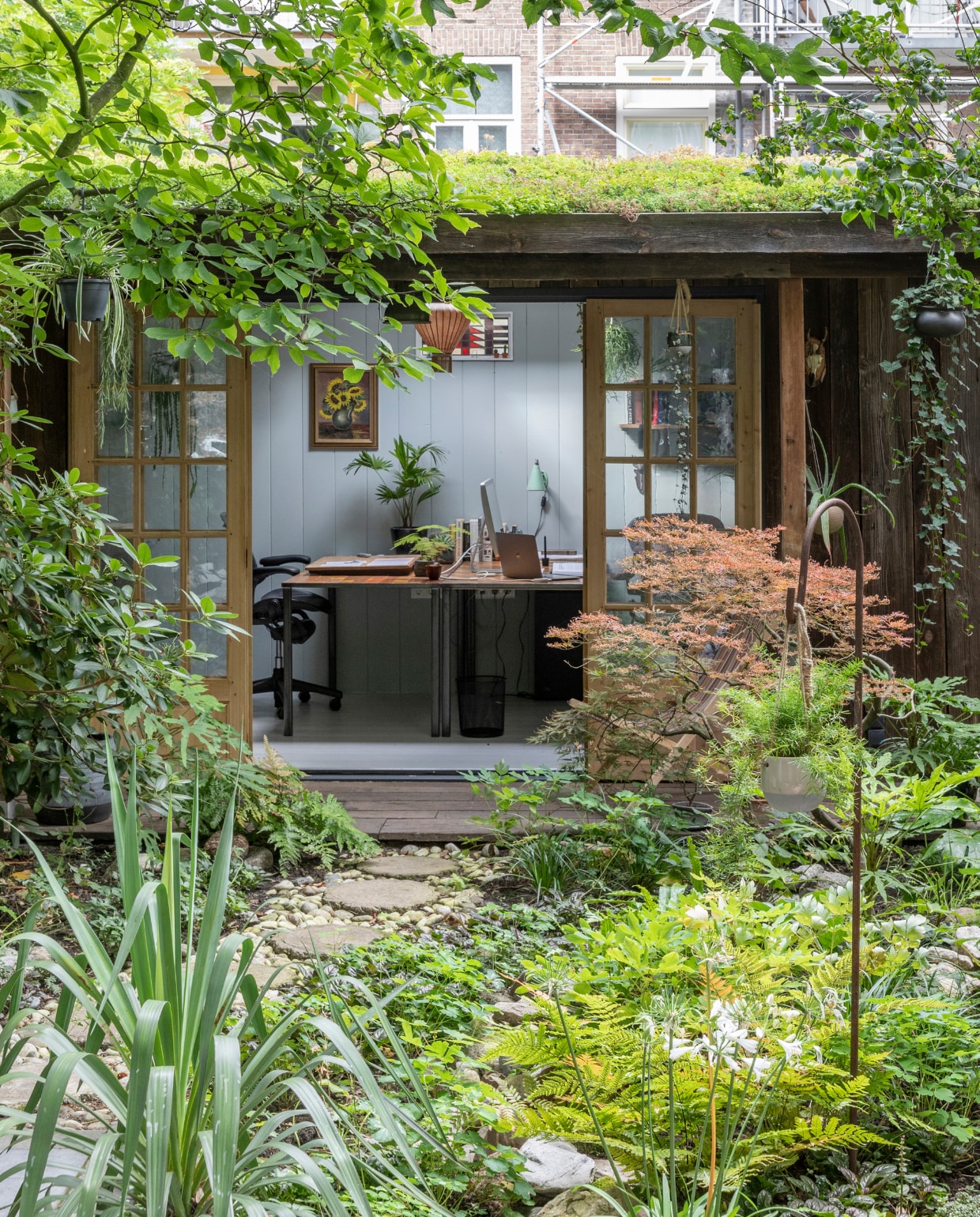 Tuinhuis ontworpen door Philip en gemaakt door timmermannen Jan en Rob. Deuren ’t Achterhuis. Planken op muur van oude schuren via Historisch Hout, net als de scheepsplanken op de veranda. Glas -in -loodraampje Marktplaats. Hanglamp Taiwan -lantern. Bureaus gemaakt door Mariekes vader. Schilderij aan muur uit Philips familie. Plantenhangers Mica. Wandlamp rommelmarktIJ -Hallen. Strandstoel al jaren in bezit, herkomst onbekend. vtwonen 04-2020 | fotografie Margriet Hoekstra