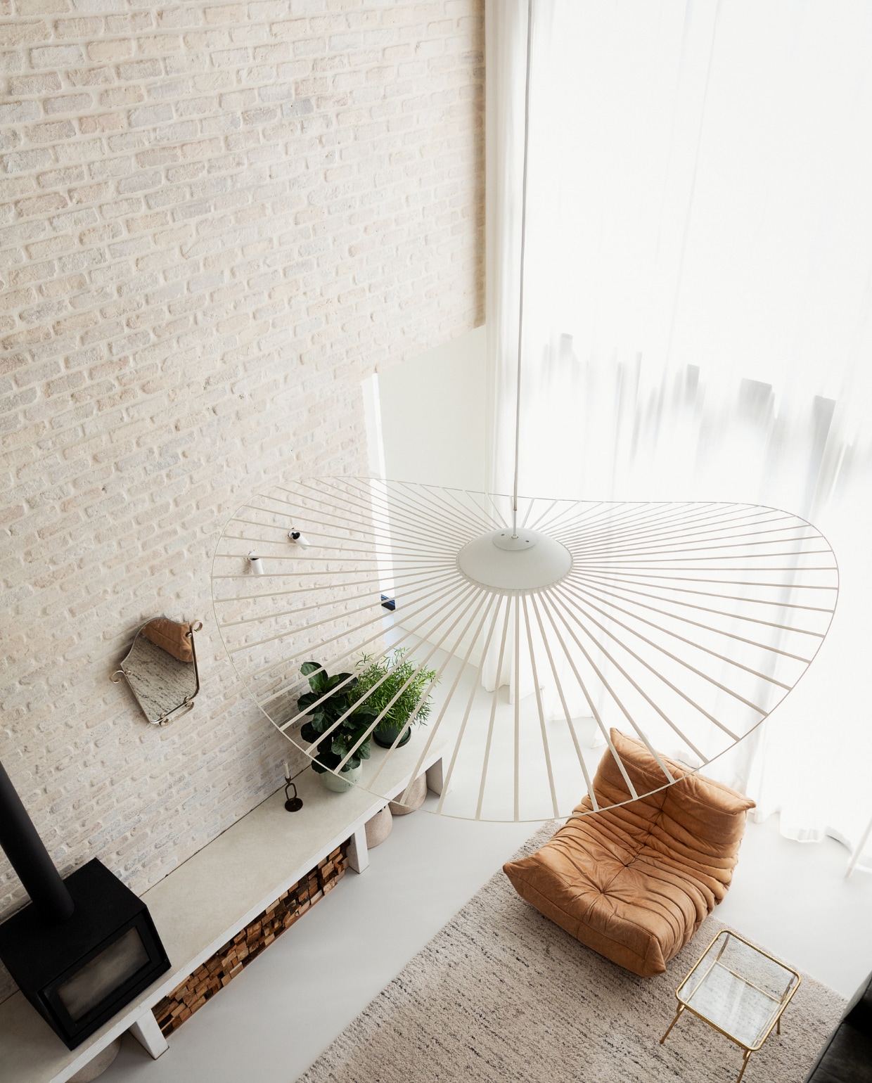 Lamp Vertigo van Petite Friture, kandelaar Zusss, kachel Barbas Bellfires, manden H&amp;M, spiegel familiestuk. Fauteuil Togo van Ligne Roset, bijzettafel Fonq, gietvloer kleurcode NCS S2000N van Alterieur. Overig onbekend. vtwonen 11-2023 | styling Ilona Jongepier | fotografie Dana van Leeuwen