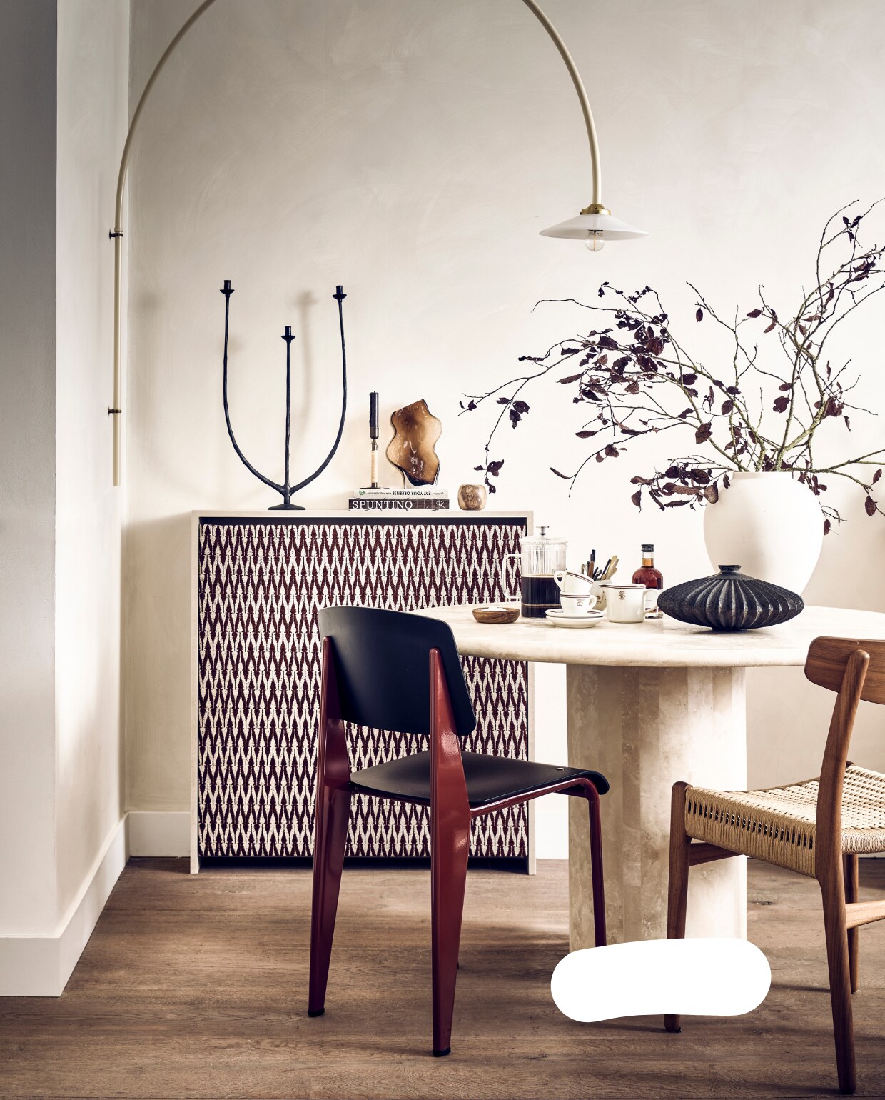 Muurverf Lime Paint in kleur Mykonos van Bauwerk (bauwerkcolour.com). Jacquard chenille-linnen stof Mio in donkerrood, 138 cm breed per meter € 59,95 (stof.nl). Wandlamp n3 Ivory € 778,- (valerie-objects.com). Rood-zwarte kunststof eetkamerstoel Standard SP van Jean Pouvré voor Vitra € 545,- (loods5). Walnoothouten stoel met gevlochten zitting CH23 van Carl Hansen € 1356,- (misterdesign.nl). Travertin dining table Bean € 2900,- (pantoufle-design.nl). Bruine glazen vaas met golven € 24,99, flesje Syrup Caramel van Nicolas Vahé € 8,99, espressokoppen en schotels per stuk € 3,99, melkkan € 3,99 (hm.com). Bruine vaas Bo op tafel € 54,95 (casagitane.com). Kookboeken € 39,95, kandelaar met 3 armen € 39,95 (sissy-boy.com). Kandelaar Duca van Menu, bronskleurige messing met rotan, € 69,- (bymolle.com). Kleine alabaster kandelaar € 24,95 (entertheloft.com). Overig privébezit. vtwonen 11-2022 | styling Kim van Rossenberg | fotografie Sjoerd Eickmans