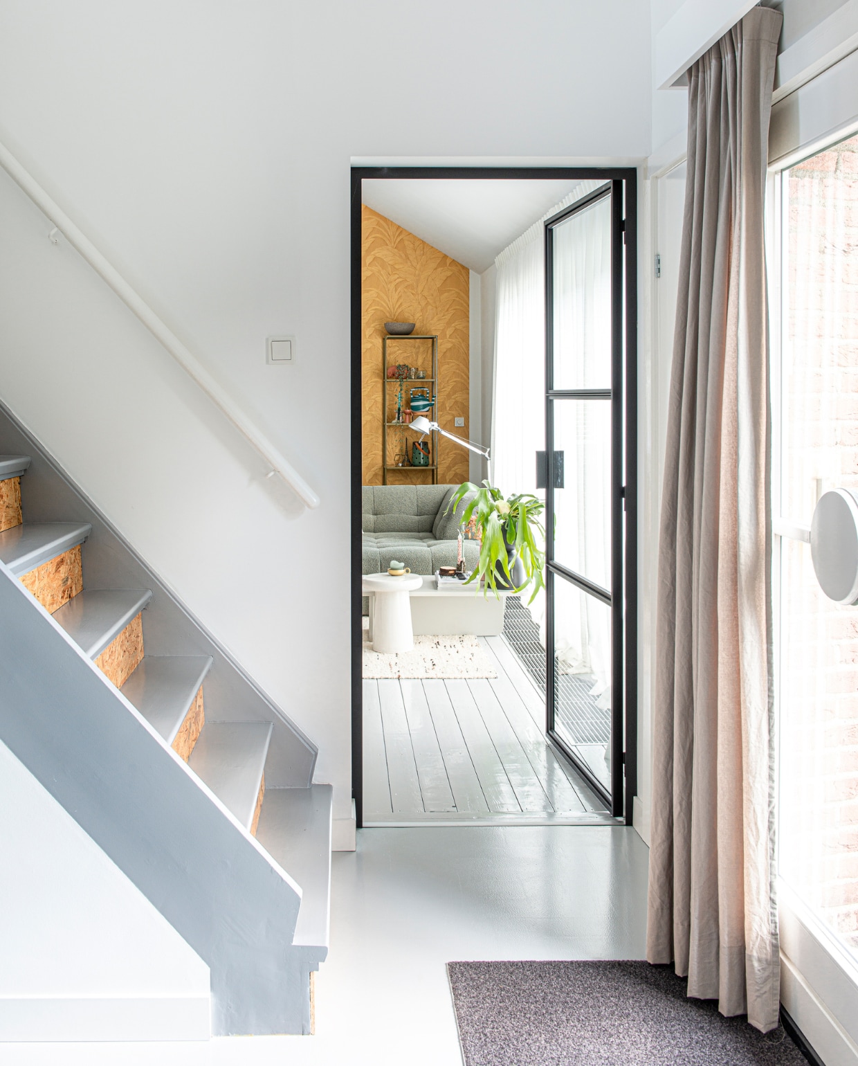 Stootborden van de trap bekleed met underlayment dat werd gelakt, stalen deur van Steellife. Overig onbekend. vtwonen special DIY 6-2022 | productie De Binnenkijkers | styling Jeske Weel | fotografie Caroline Coehorst