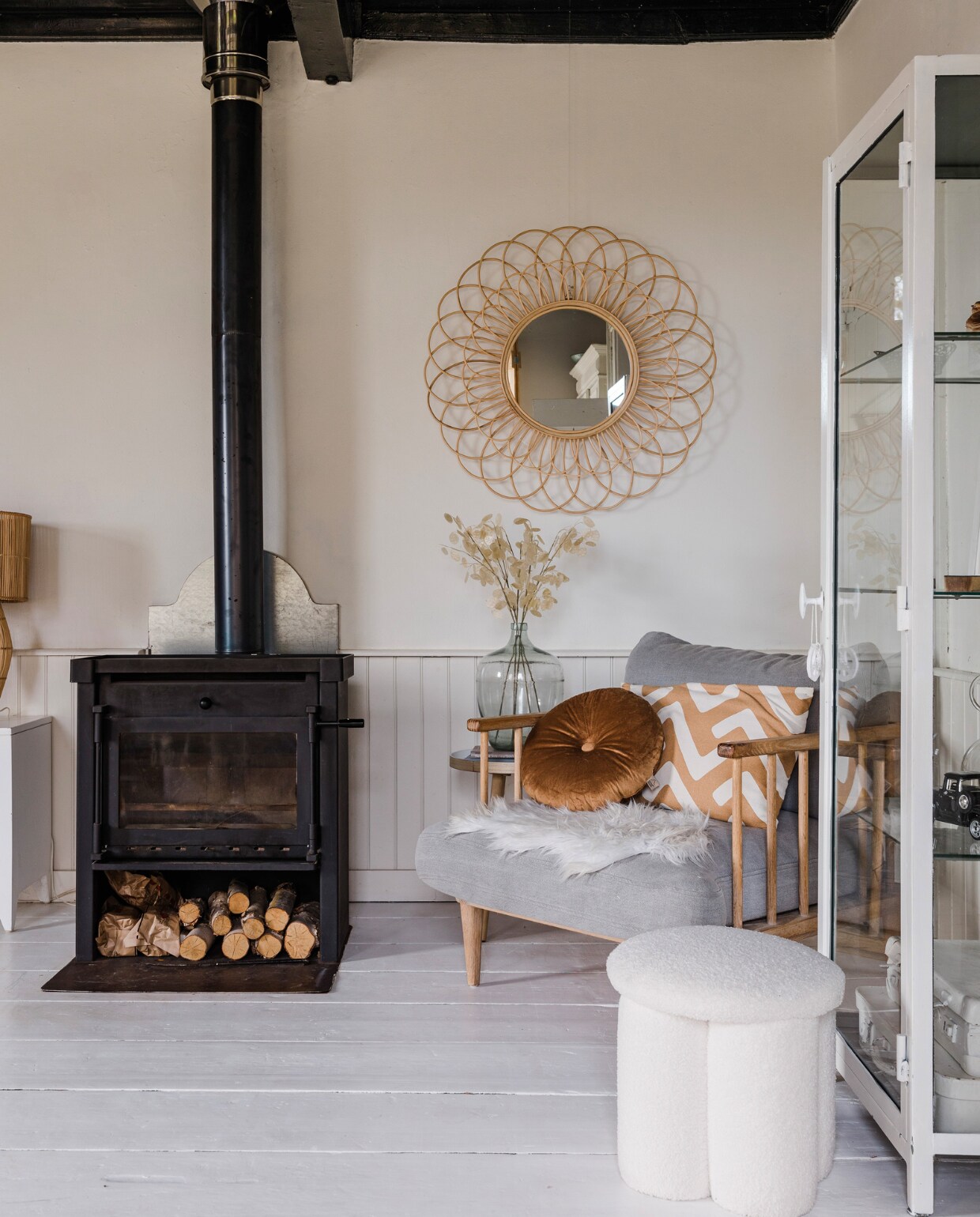 Kachel zat al in het huis. Fauteuil Loods 5, bruin kussen Dutch Decor, bruin-wit kussen H&amp;M Home. Vacht en bijzettafel Kwantum. Poef Karwei, vitrinekast van vtwonen, wit geschilderd. Spiegel Leen Bakker, gistfles brocantemarkt, kunstbloemen Jysk. Overig onbekend. vtwonen 12-2023 | styling Anouschka Witteveen | fotografie Corine Hoge Bavel